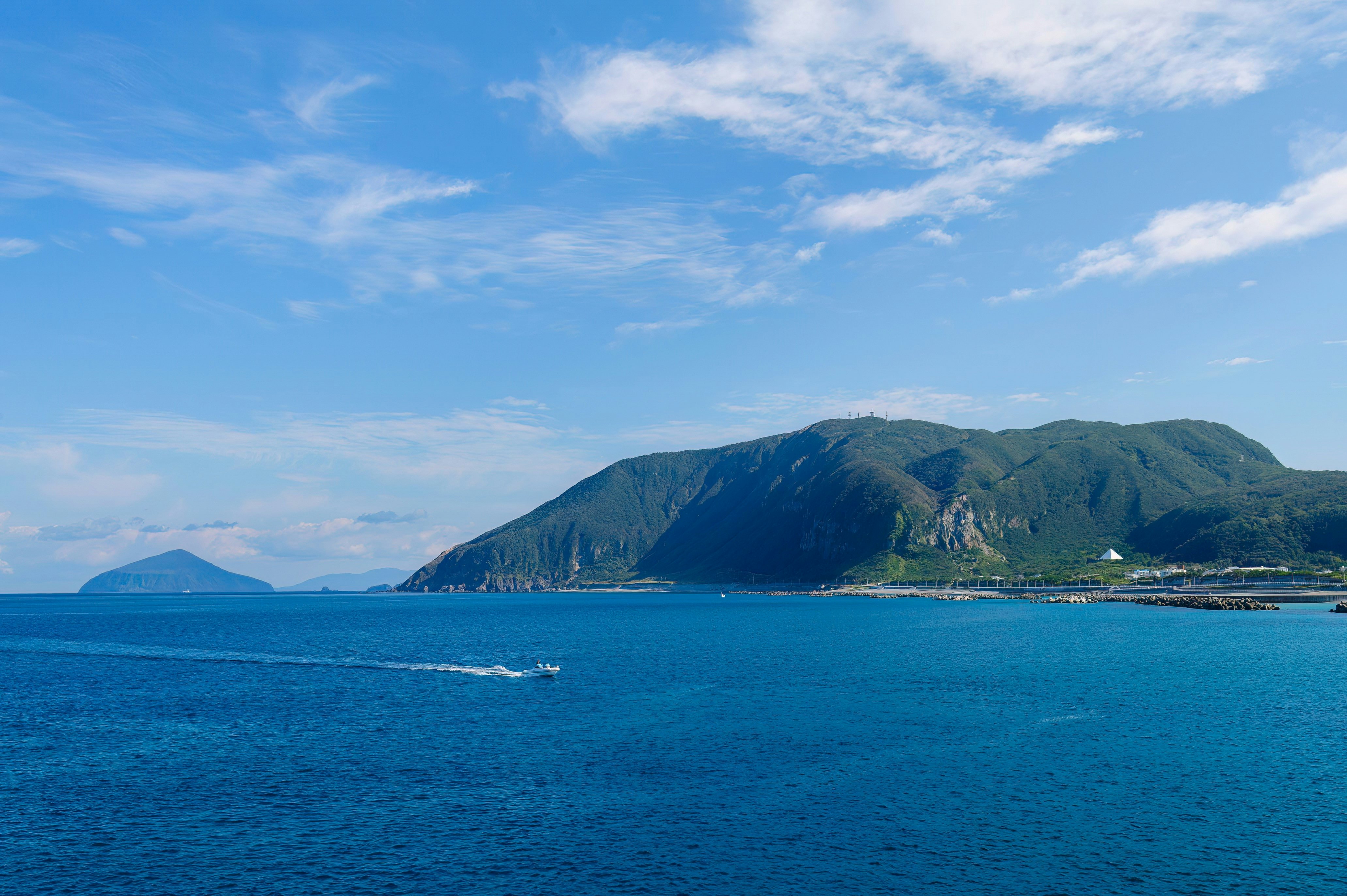 Islands dotted through the ocean with a small speedboat sailing by.