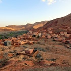 Aerial view of the Berber village of Ait Ouglif, Dades Gorges Valley in the High Atlas Mountains, Morocco at dusk. The houses, Mosque and hotels match the orange brown colour of the rugged landscape., License Type: media, Download Time: 2025-06-17T17:41:53.000Z, User: mvm_lonelyplanet, Editorial: false, purchase_order: 56530 - Guidebooks, job: Experience Morocco 1, client: Global Publishing-WIP, other: Virginia Moreno