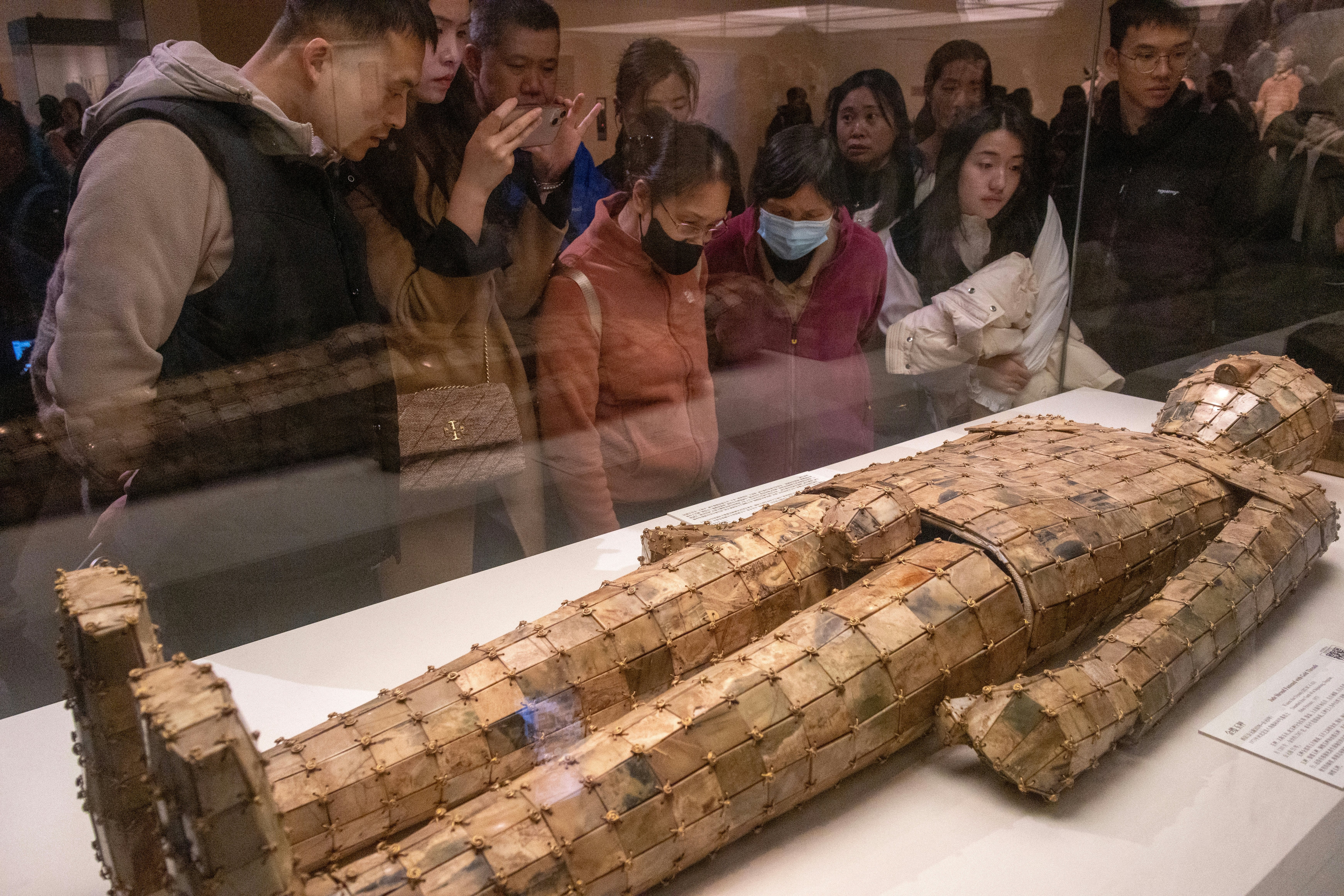 People cluster by a case enclosing a burial suit made of jade plaques in Beijing's National Museum.
