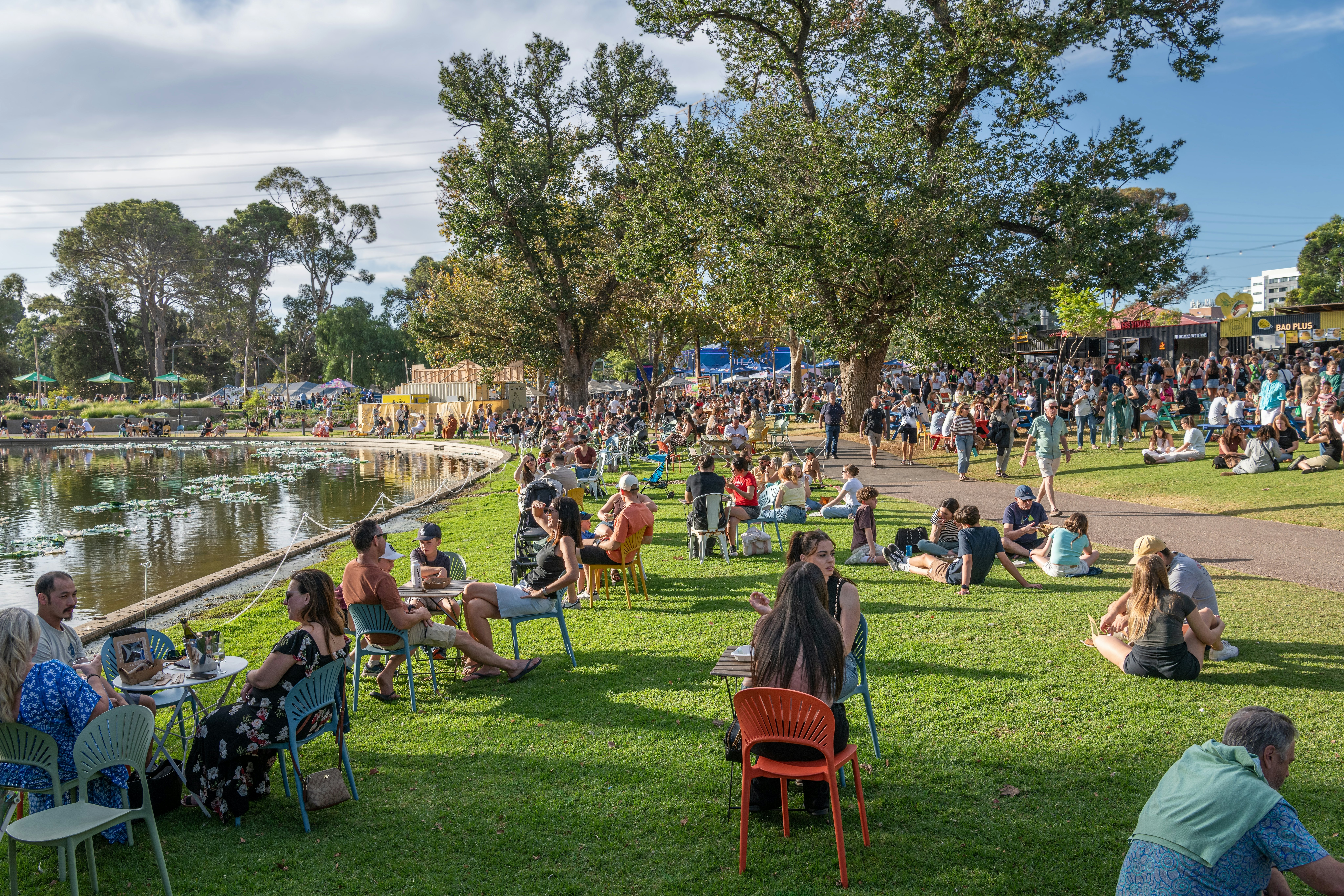 People gathered in parkland around a lake during a summer festival.