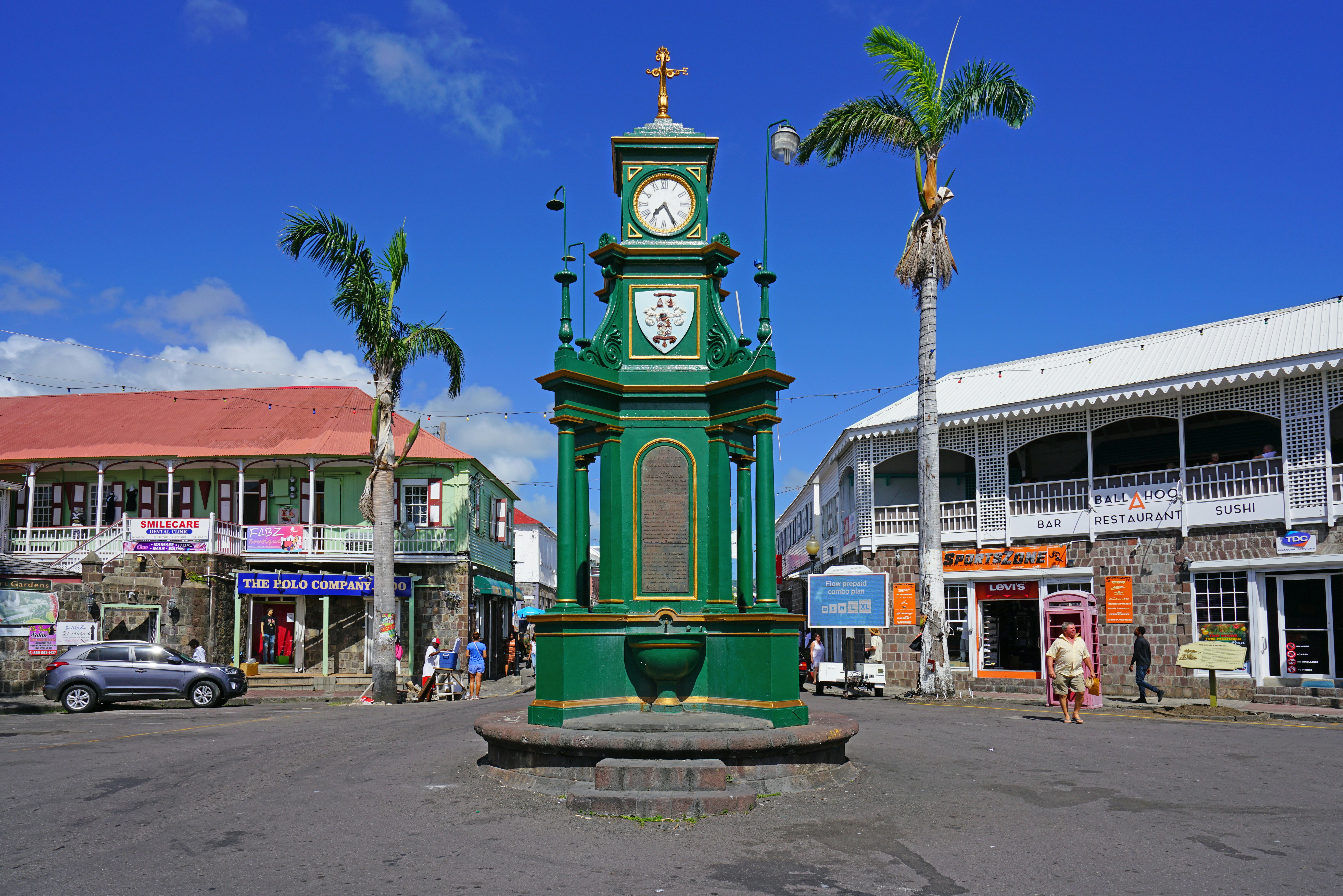The green Berkeley Memorial Clock in Basseterre's Circus, with pedestrians walking nearby