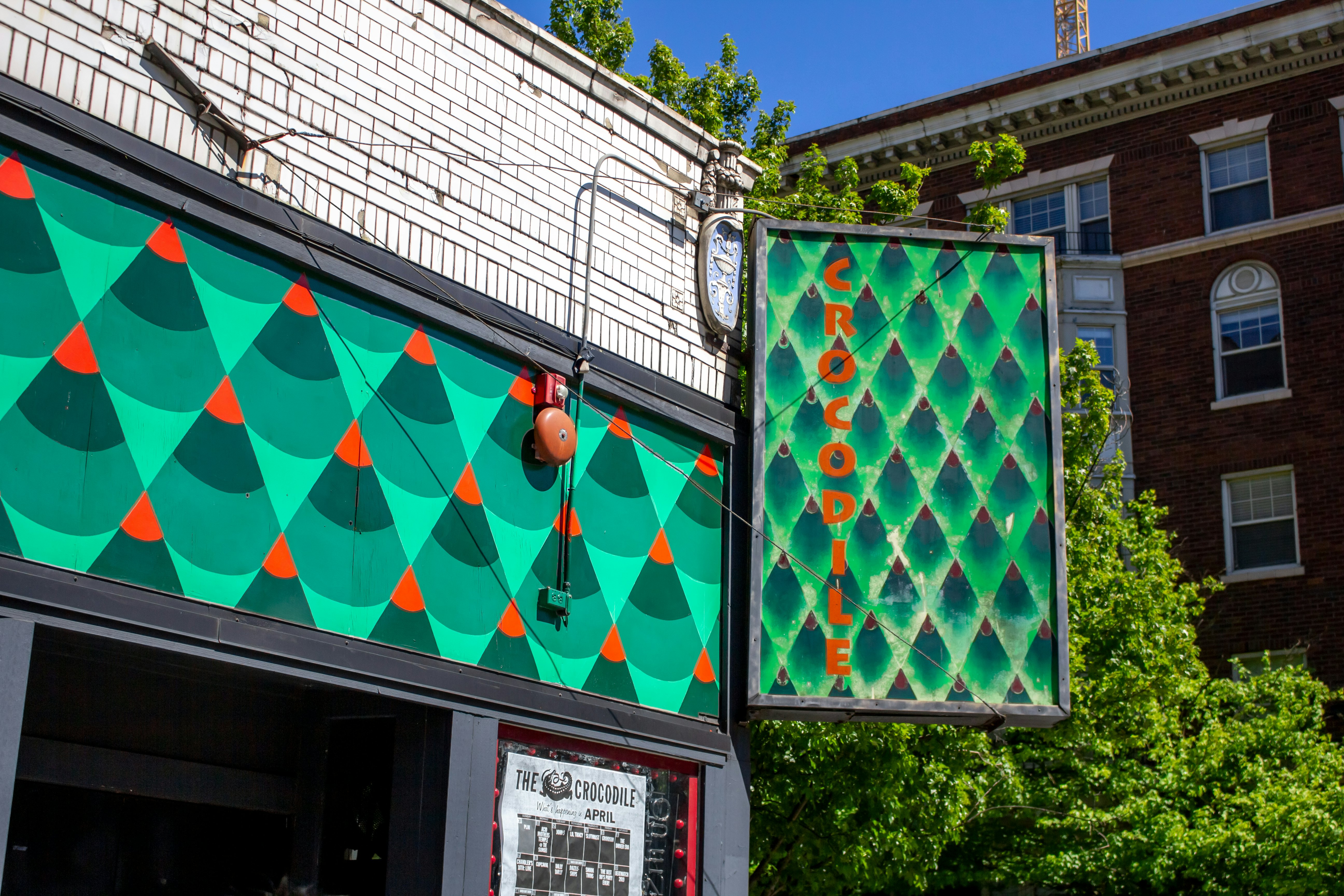 The exterior of a live music venues with a green patterned sign that says "Crocodile" in red writing.
