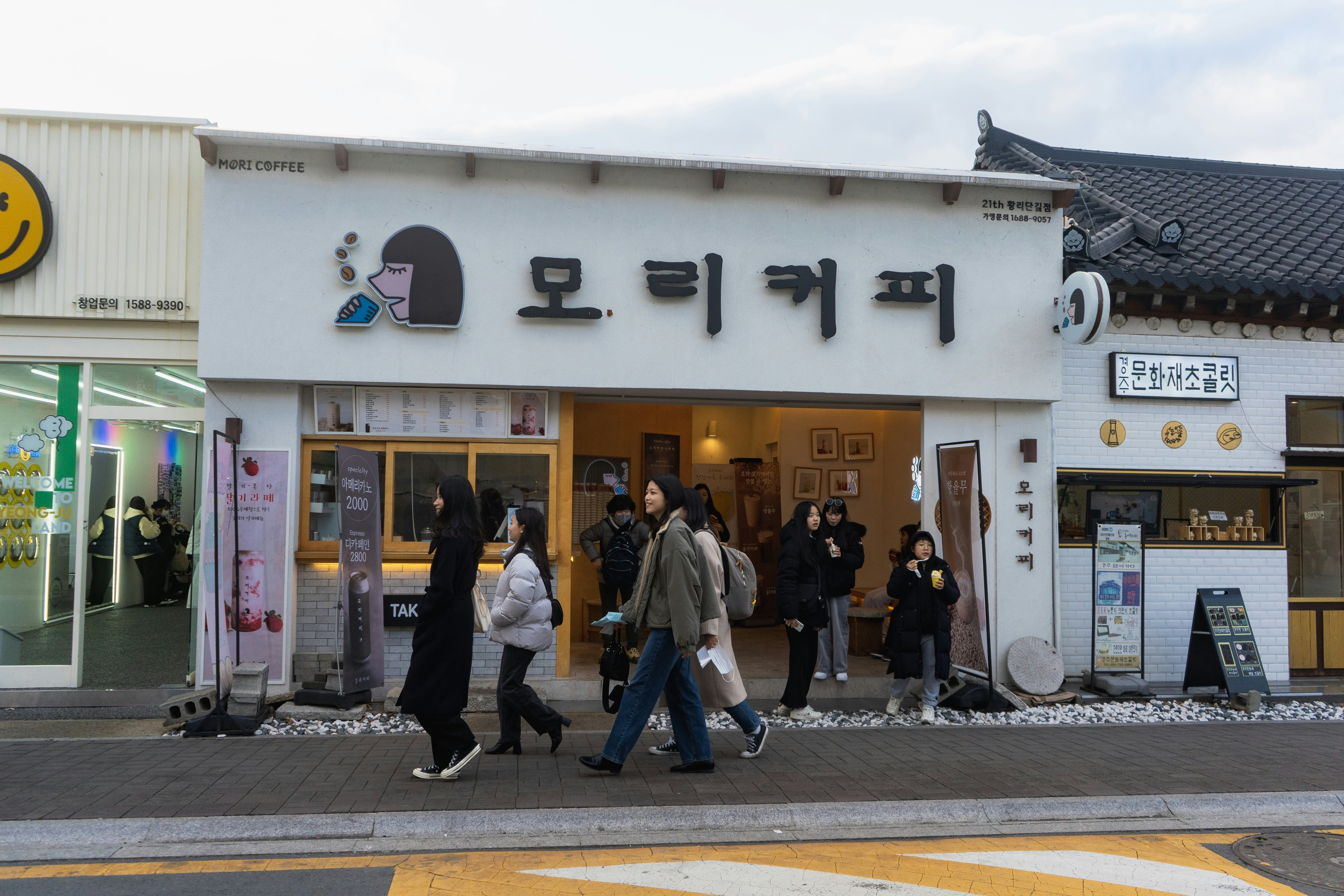 People in winter coats walking by a cafe