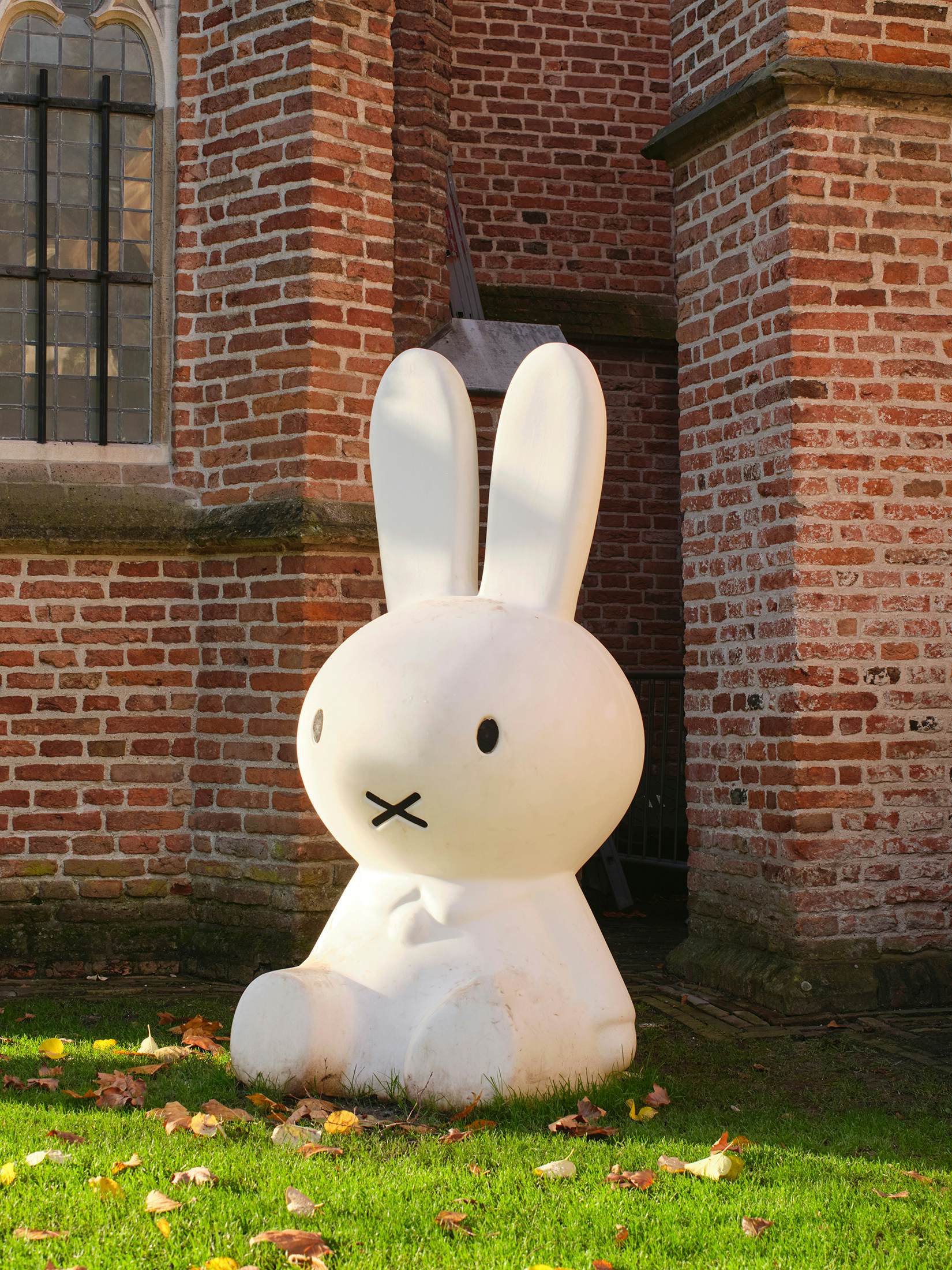 A giant stuffed bunny leans against a church wall.
