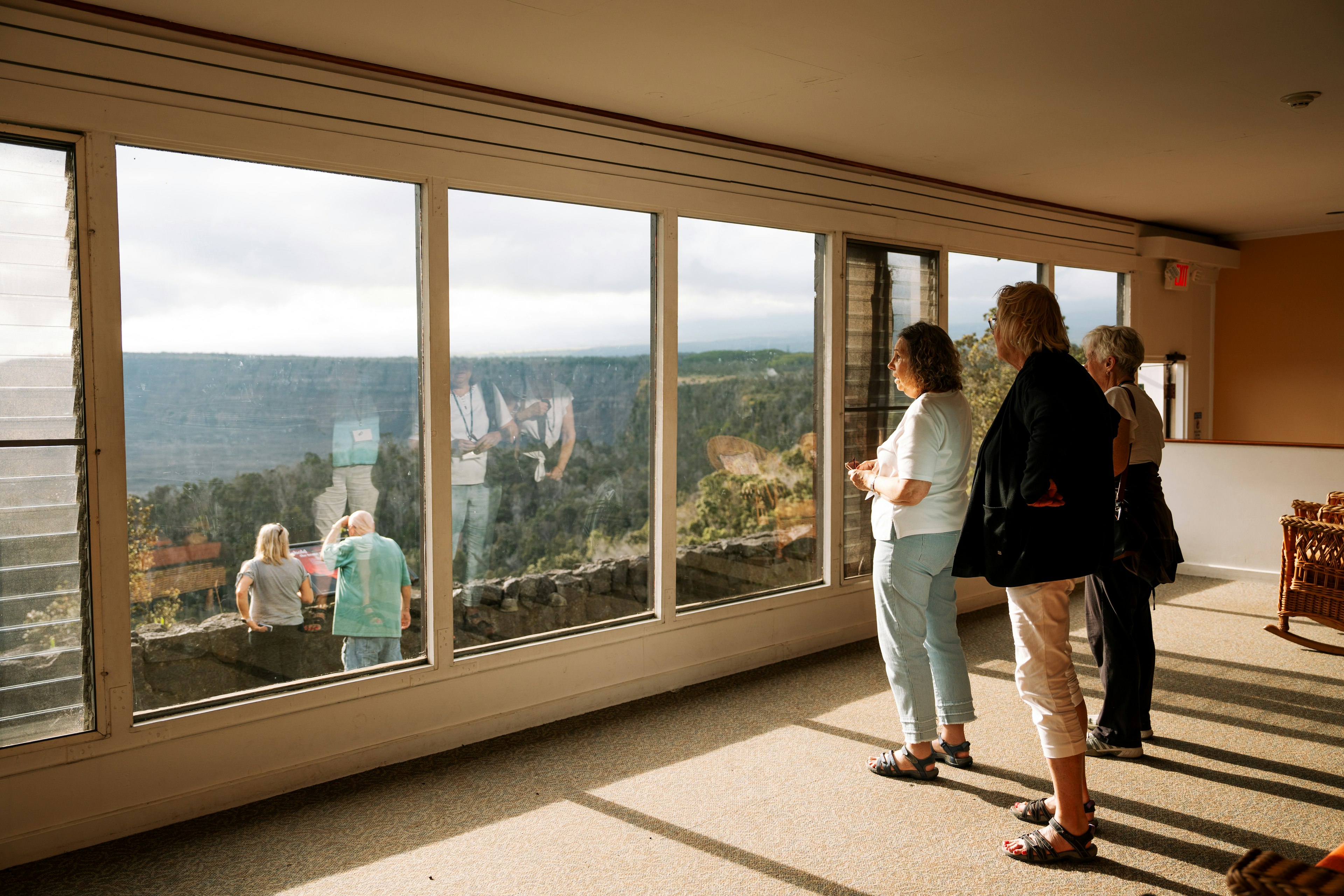 People stare out of a large window overlooking a crater