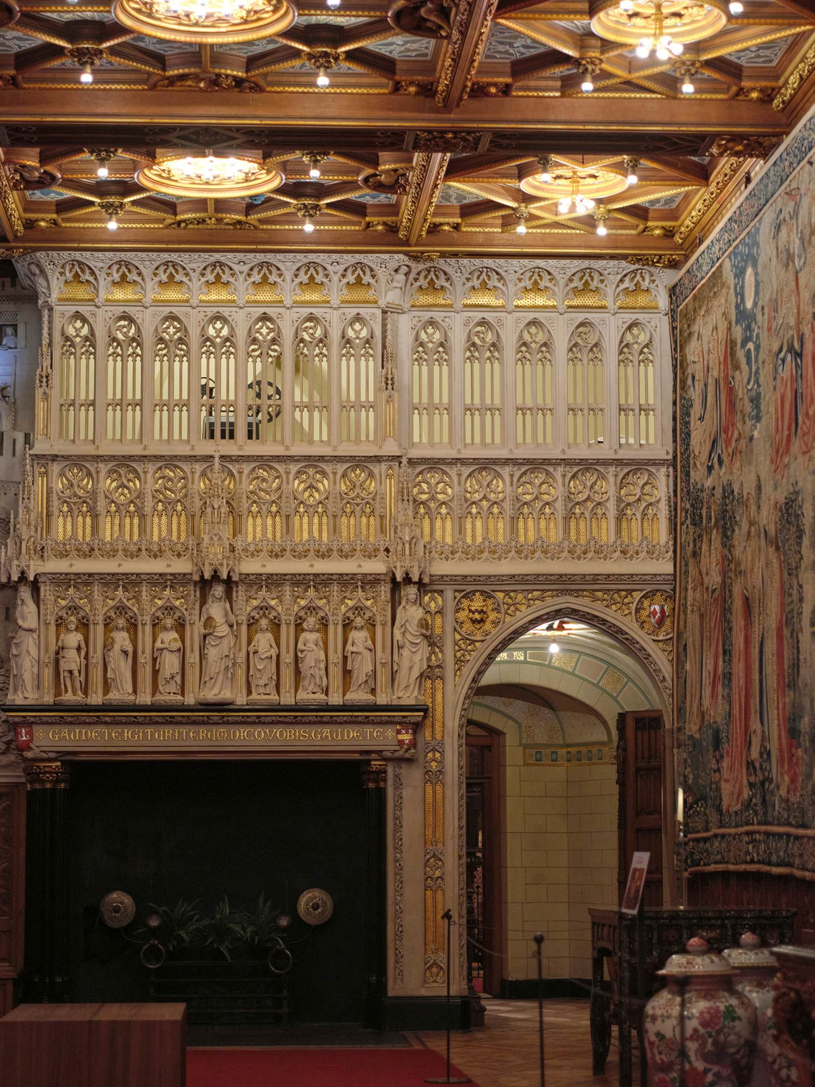 Gold tapestries, carvings and sculptures are displayed on a castle wall.