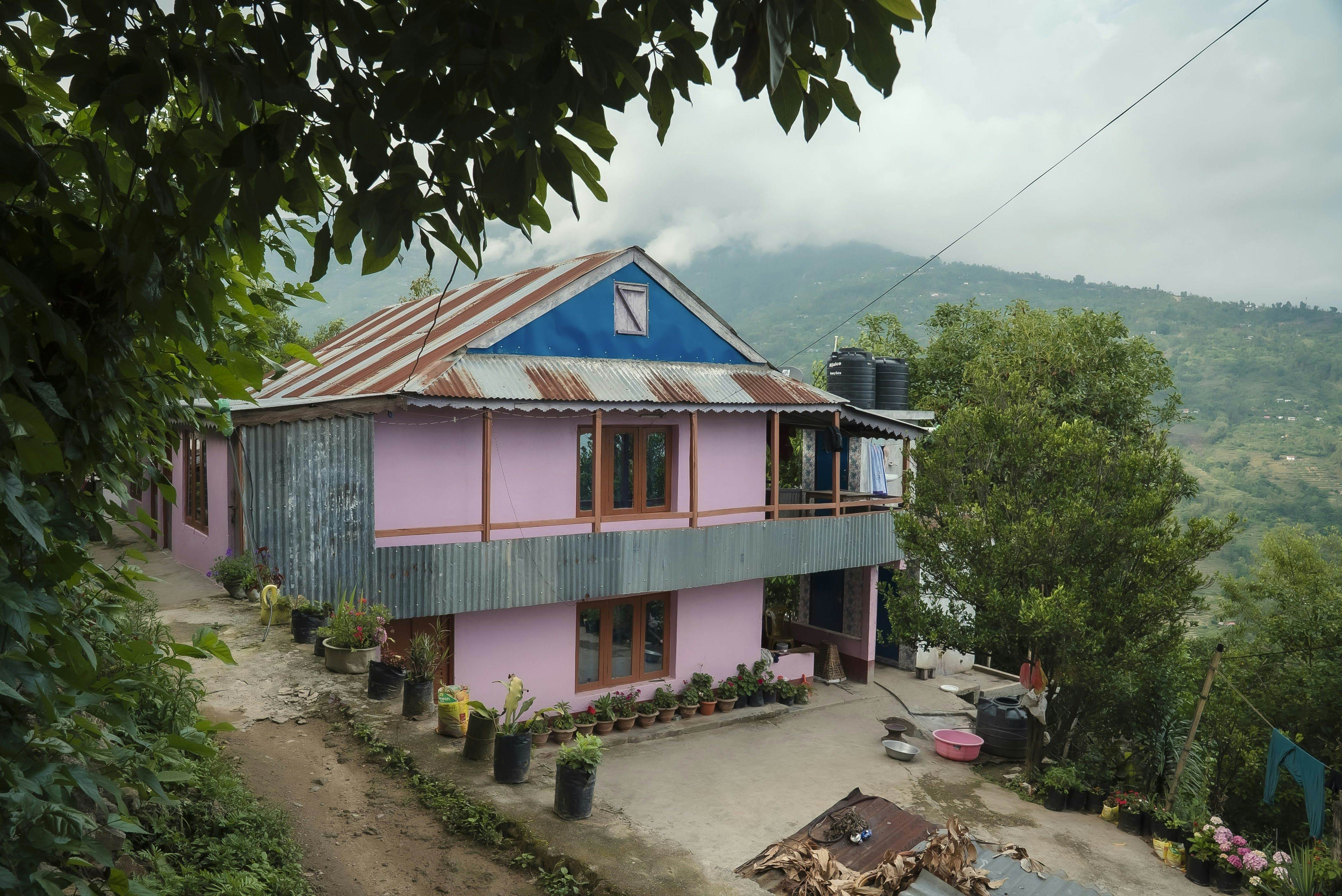 A pink house in Nepal; a mountainscape is in the background.