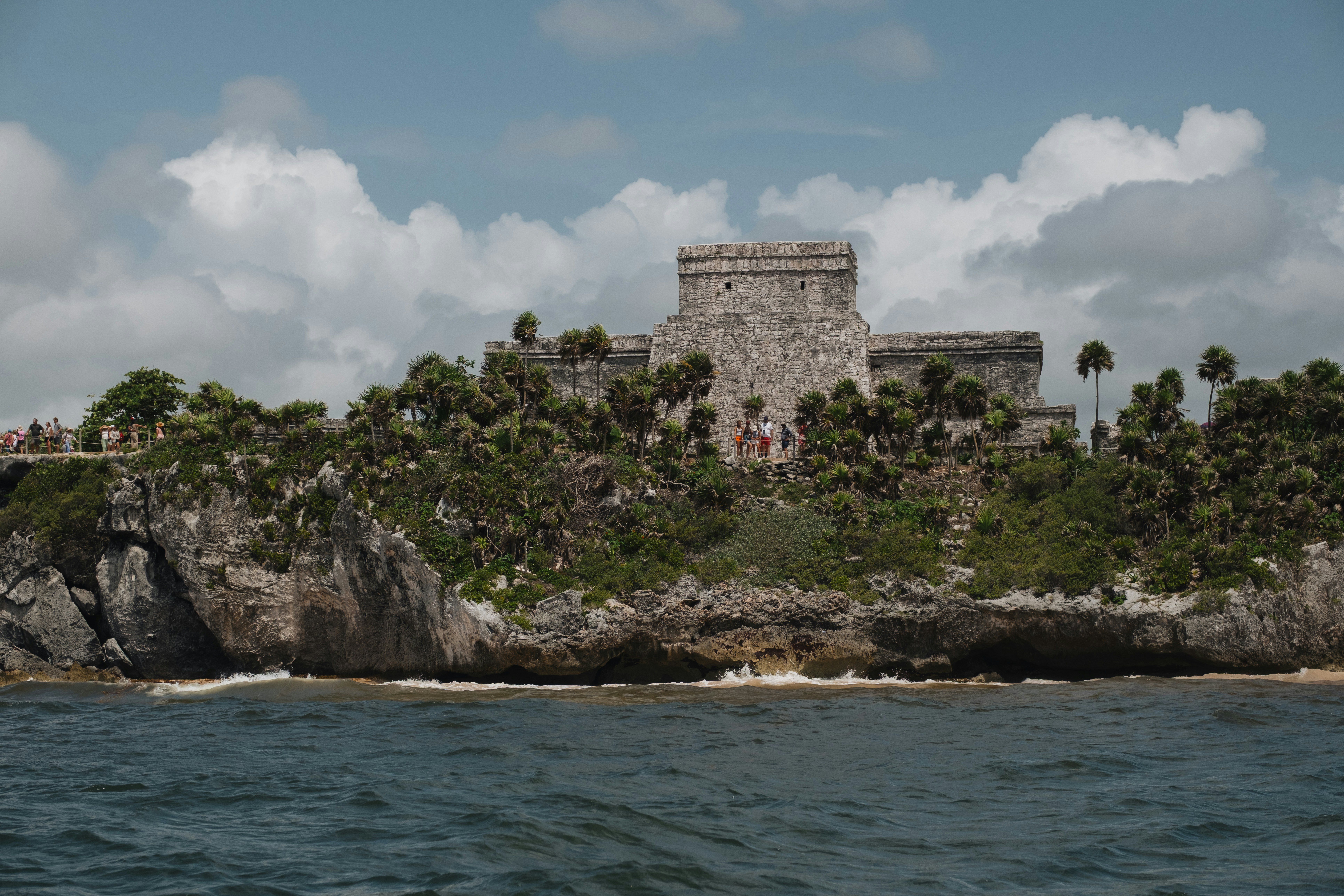 An ancient stone temple at the edge of the coast on a gray day.