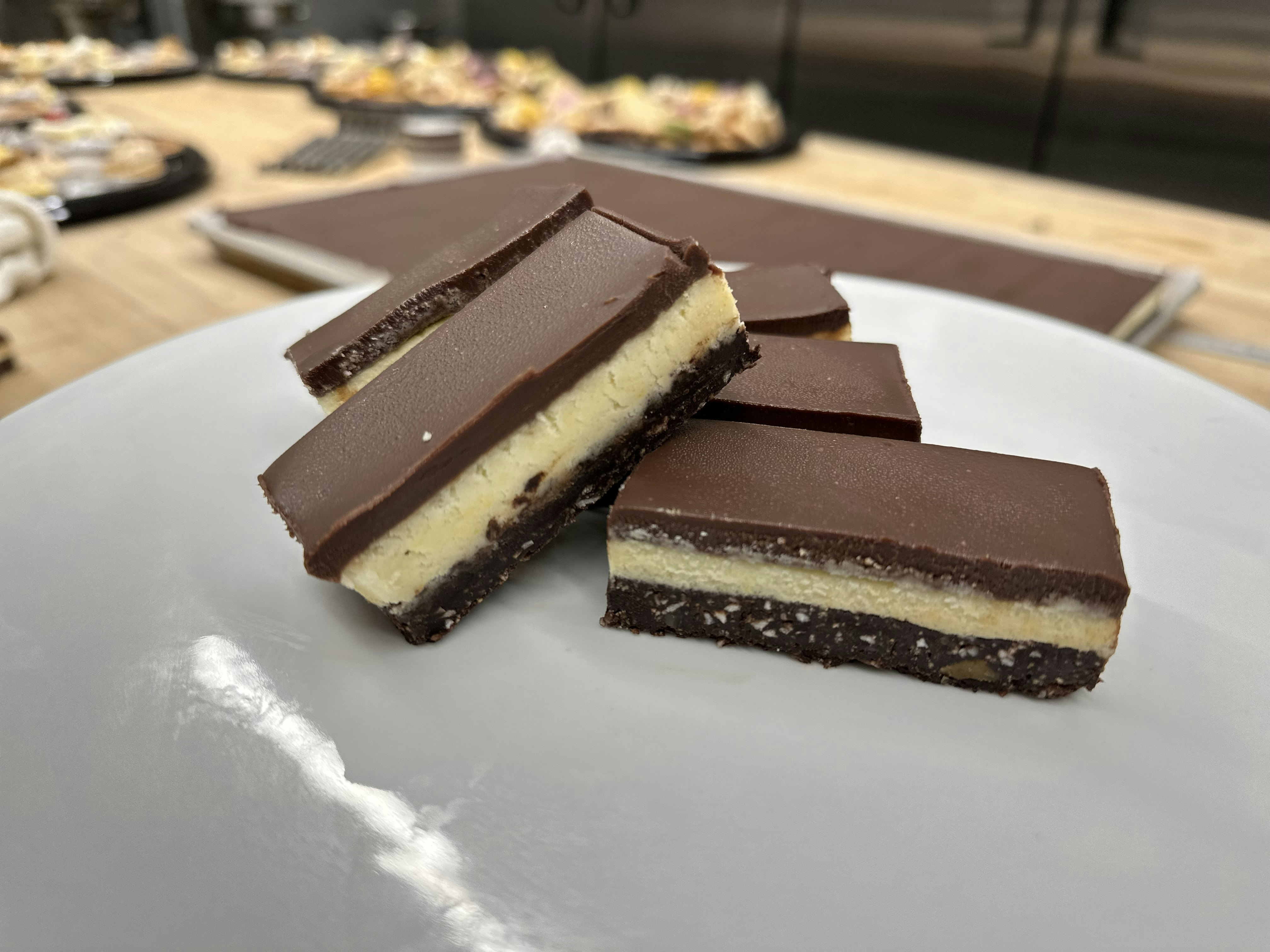 A white plate with several chocolate-based layered bars stacked on it.