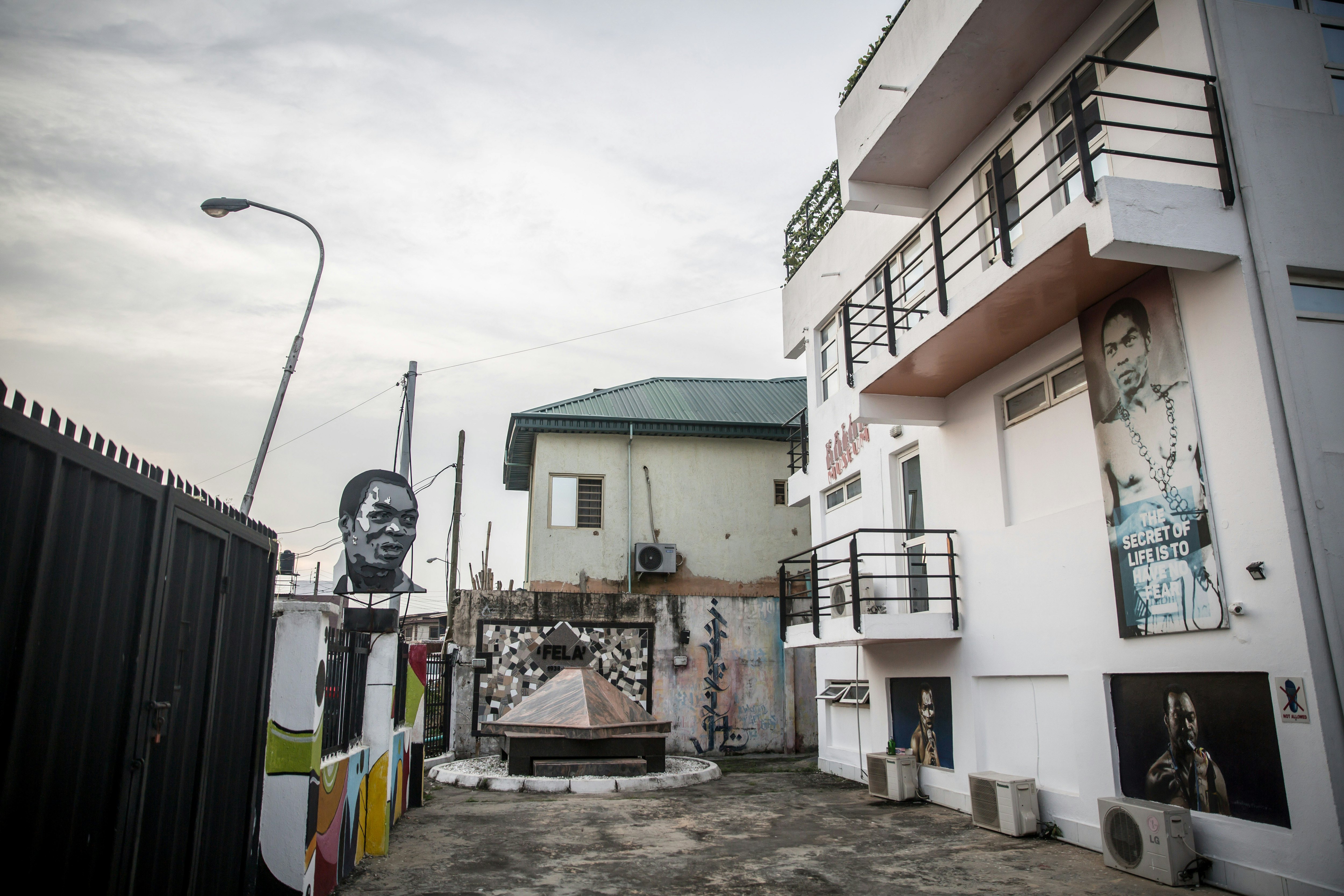 Two stucco buildings surround a courtyard. Murals decorate the walls of the buildings.