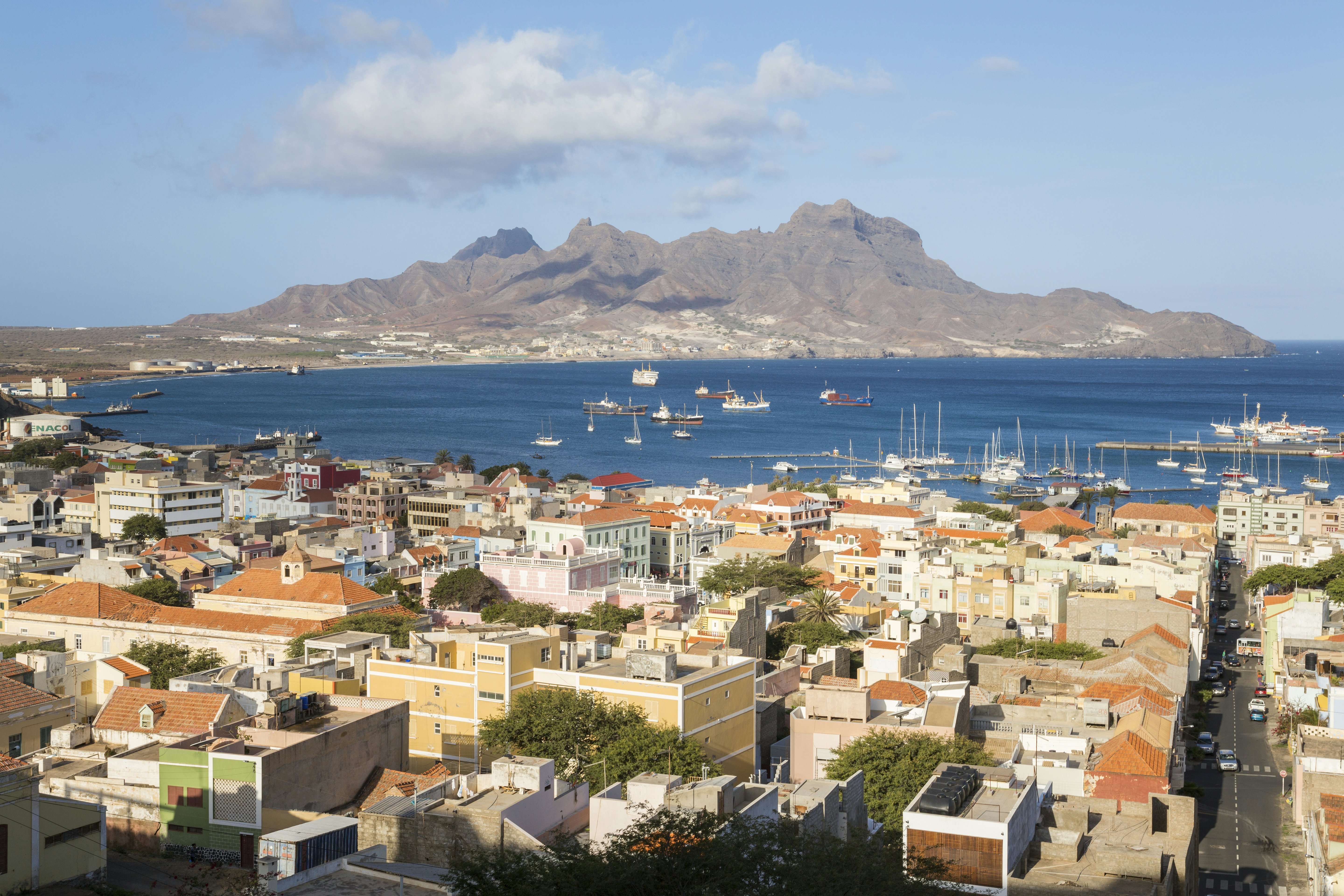 A low-rise island city with a sailboats moored in its sheltered bay.