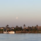 LUXOR, EGYPT. APRIL 2025.
The moon at sunrise on the Nile River in Luxor, as seen from aboard a riverboat.
