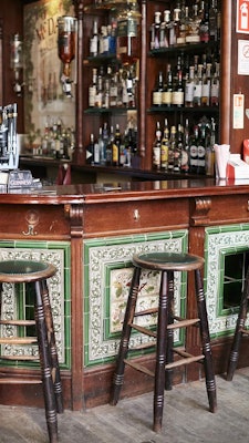 Two men dressed in white work behind an ornate bar