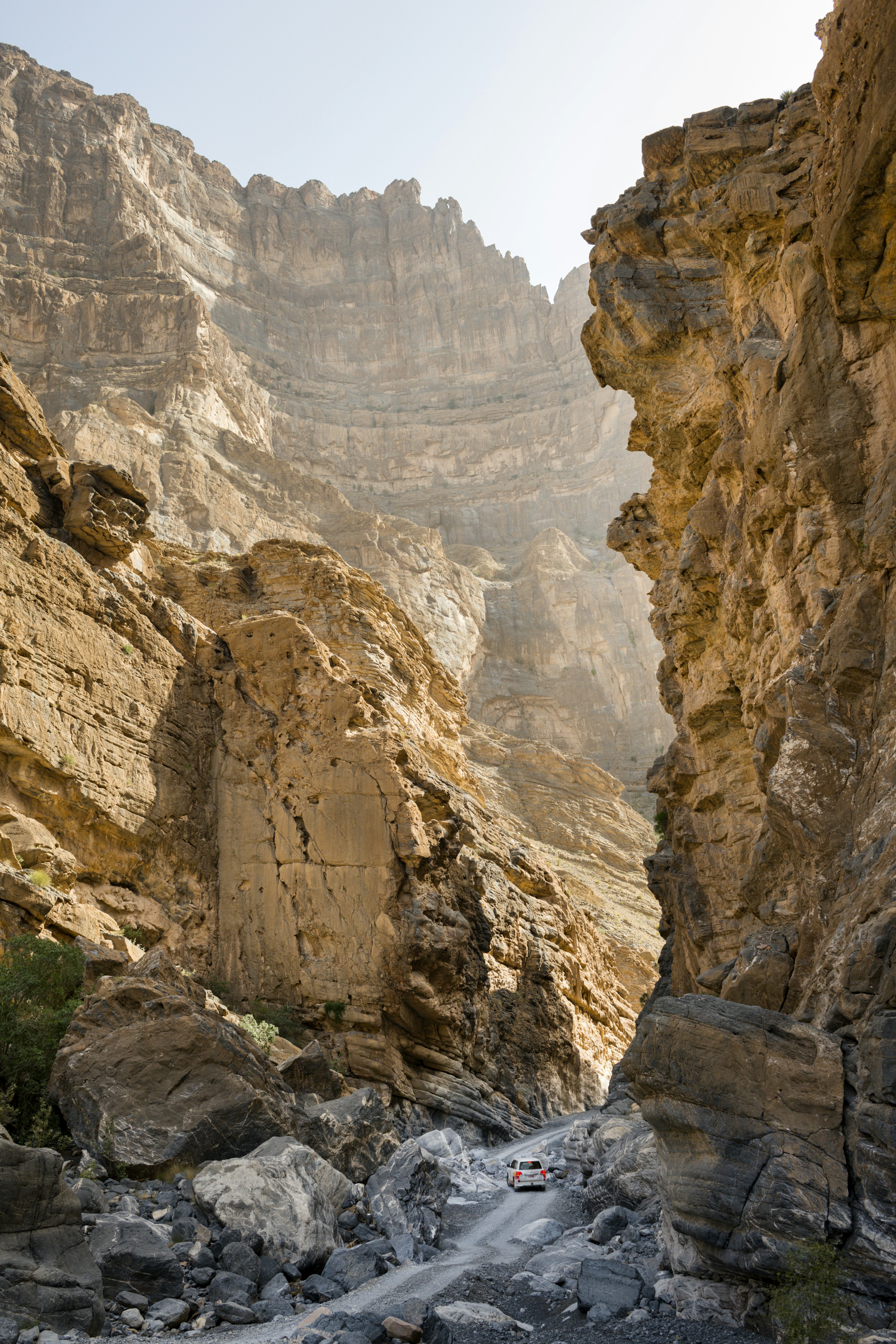 A white car driving between large rocks on Wadi Ghul in Oman