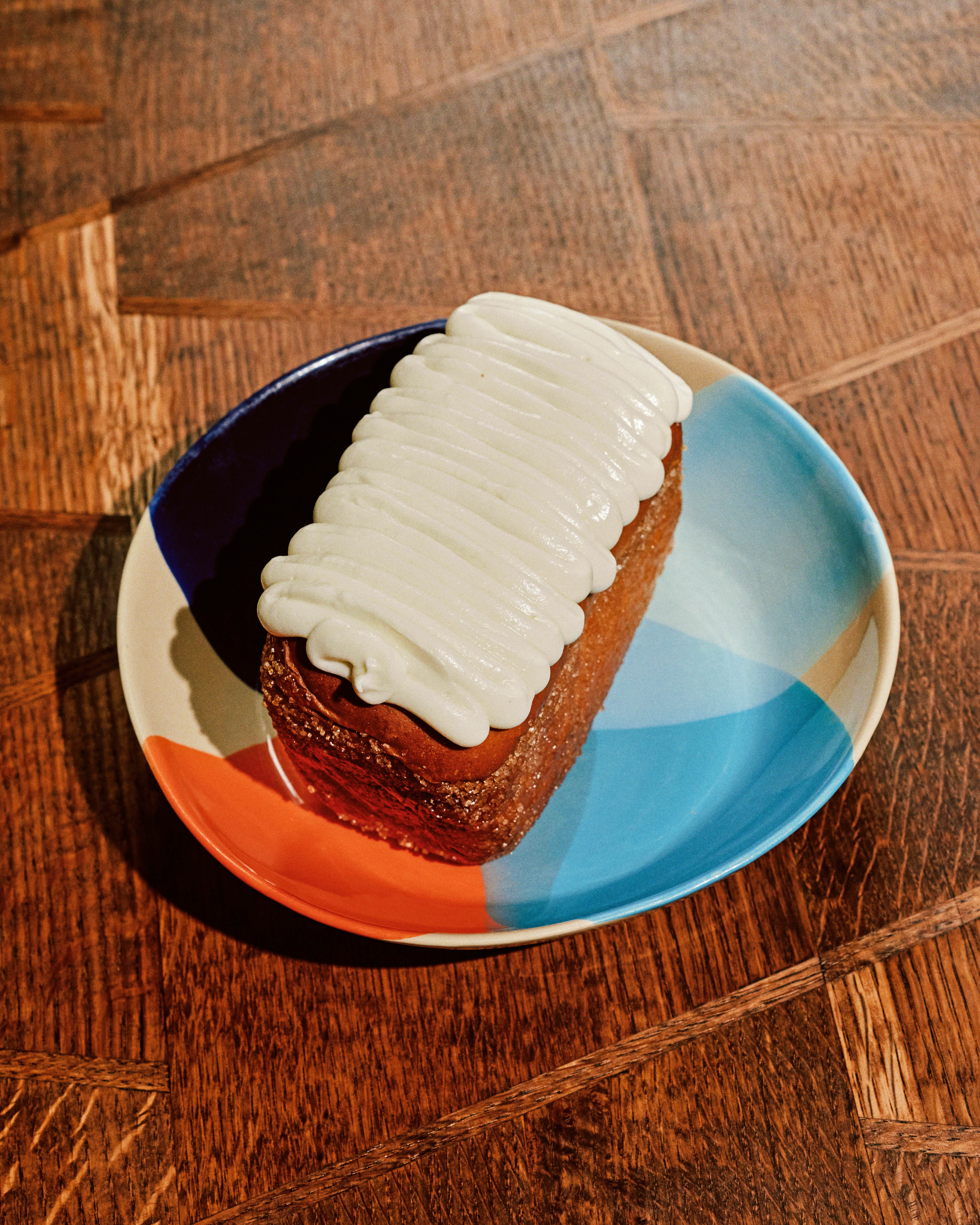 A coconut turnover on a colorful dessert plate on a wooden table. 
