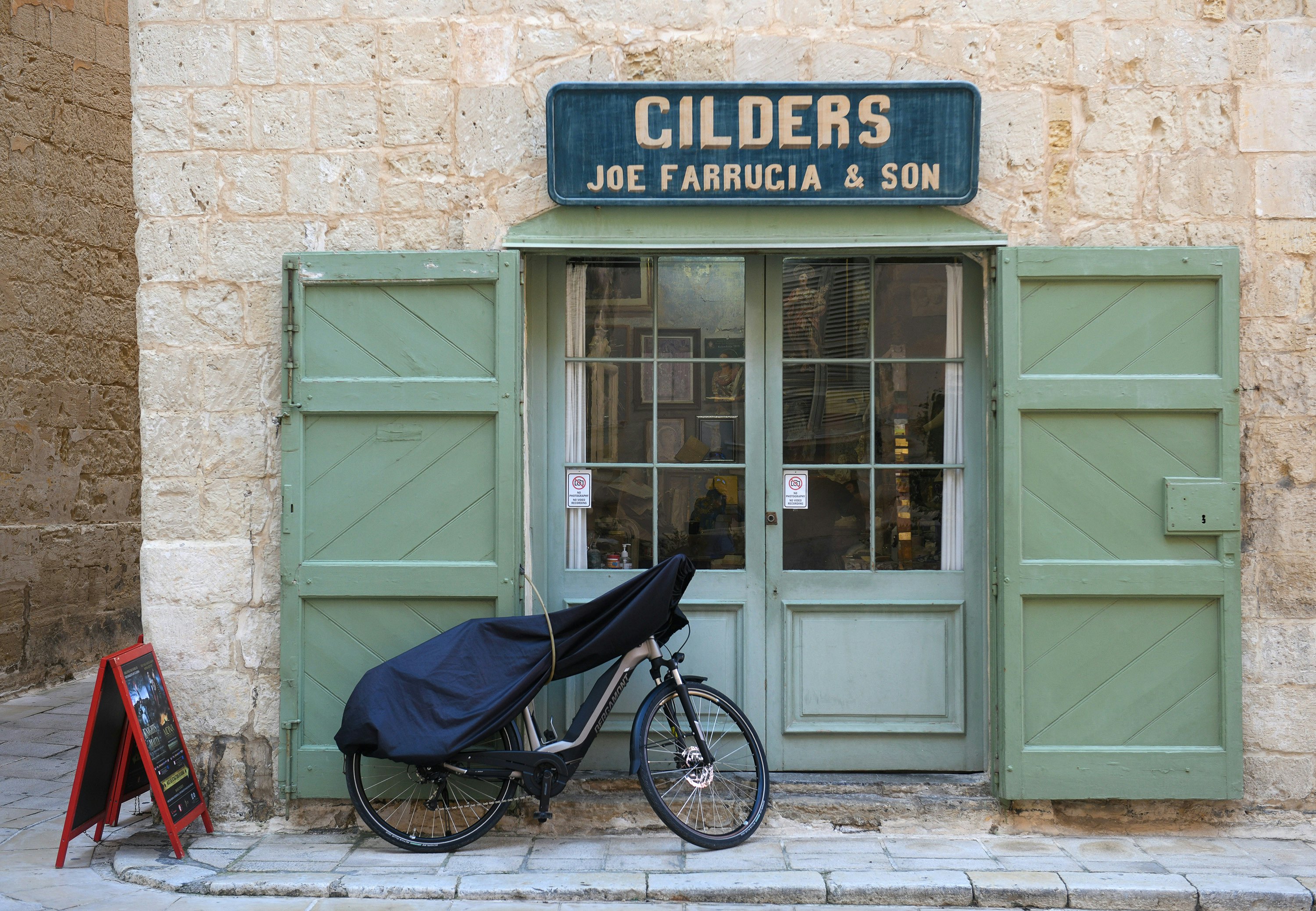A bike parked outside a cafe with green shutters