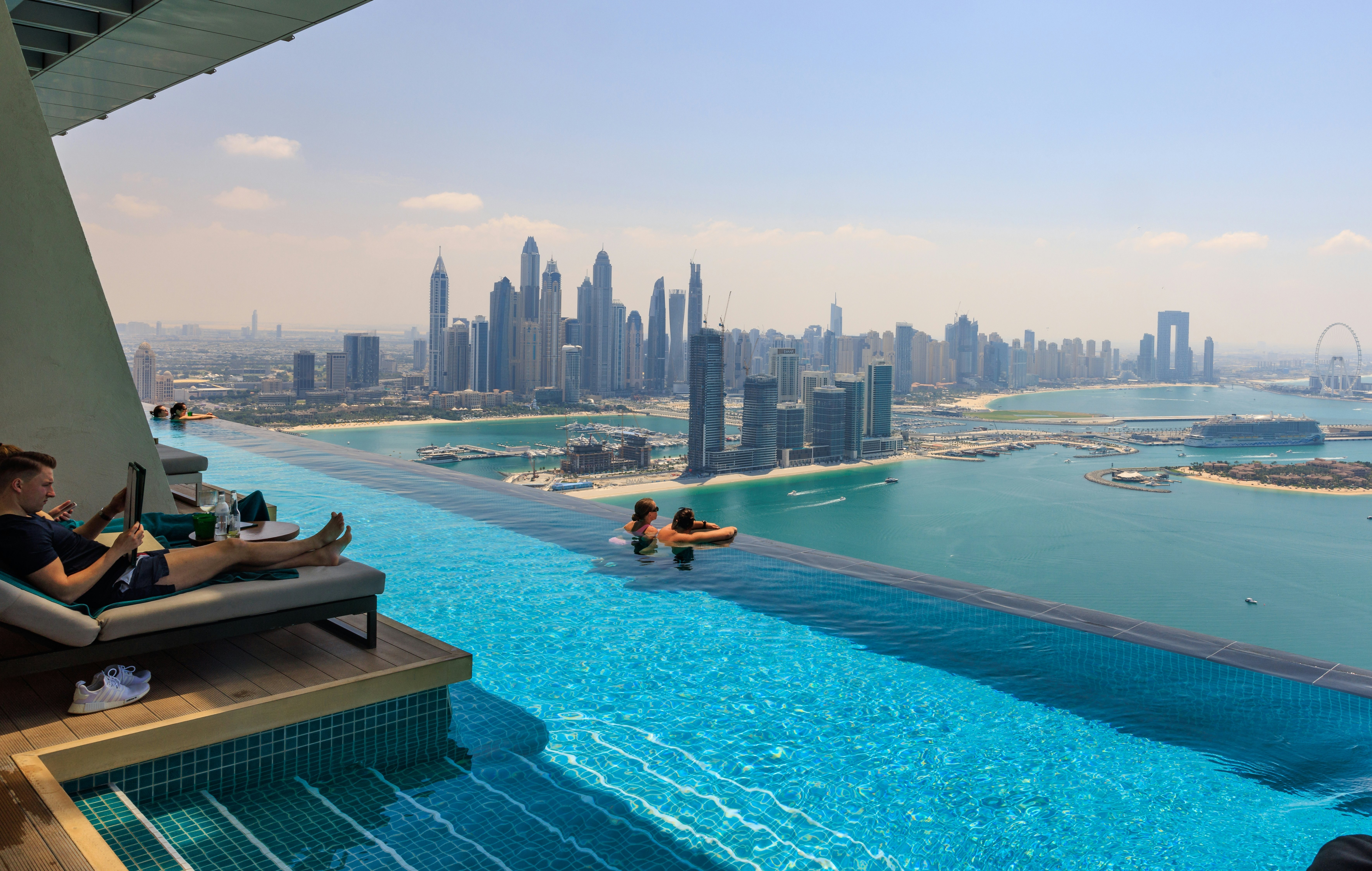 Tourists relaxing in AURA sky pool bar, the world's highest 360 degree infinity pool on Palm Jumeirah overlooking Dubai Marina skyline - Dubai, UAE