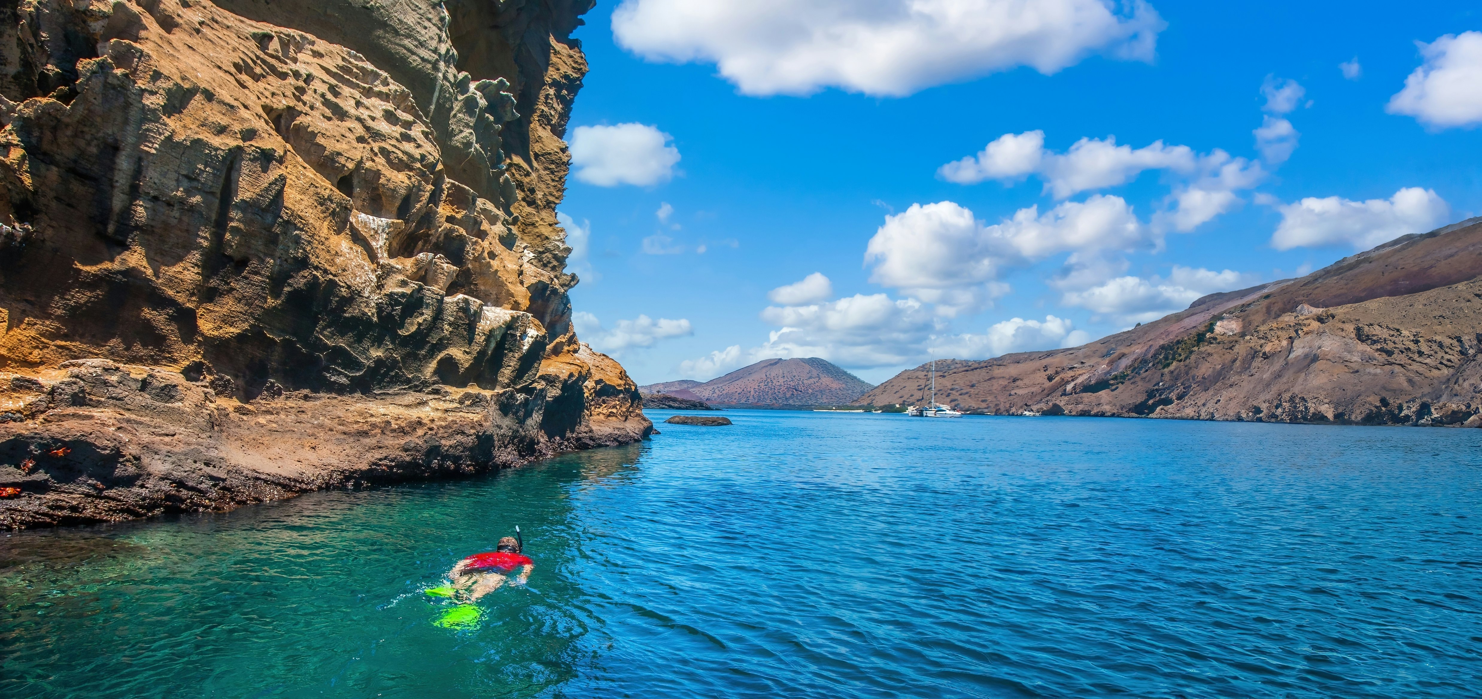 Person snorkeling next to a cliff face in the Galápagos Islands