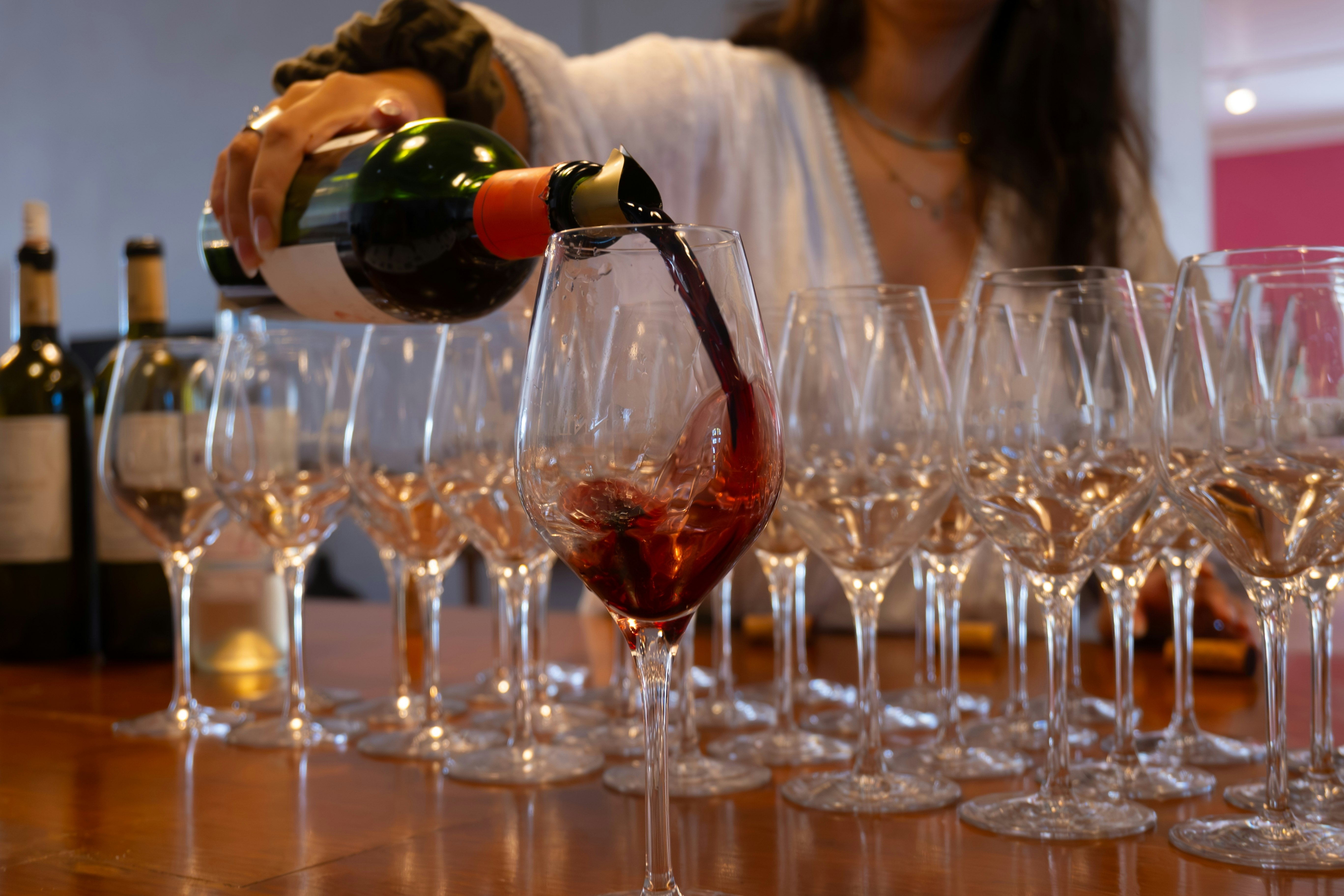 A sommelier pours red wine into a glass at a wine tasting.