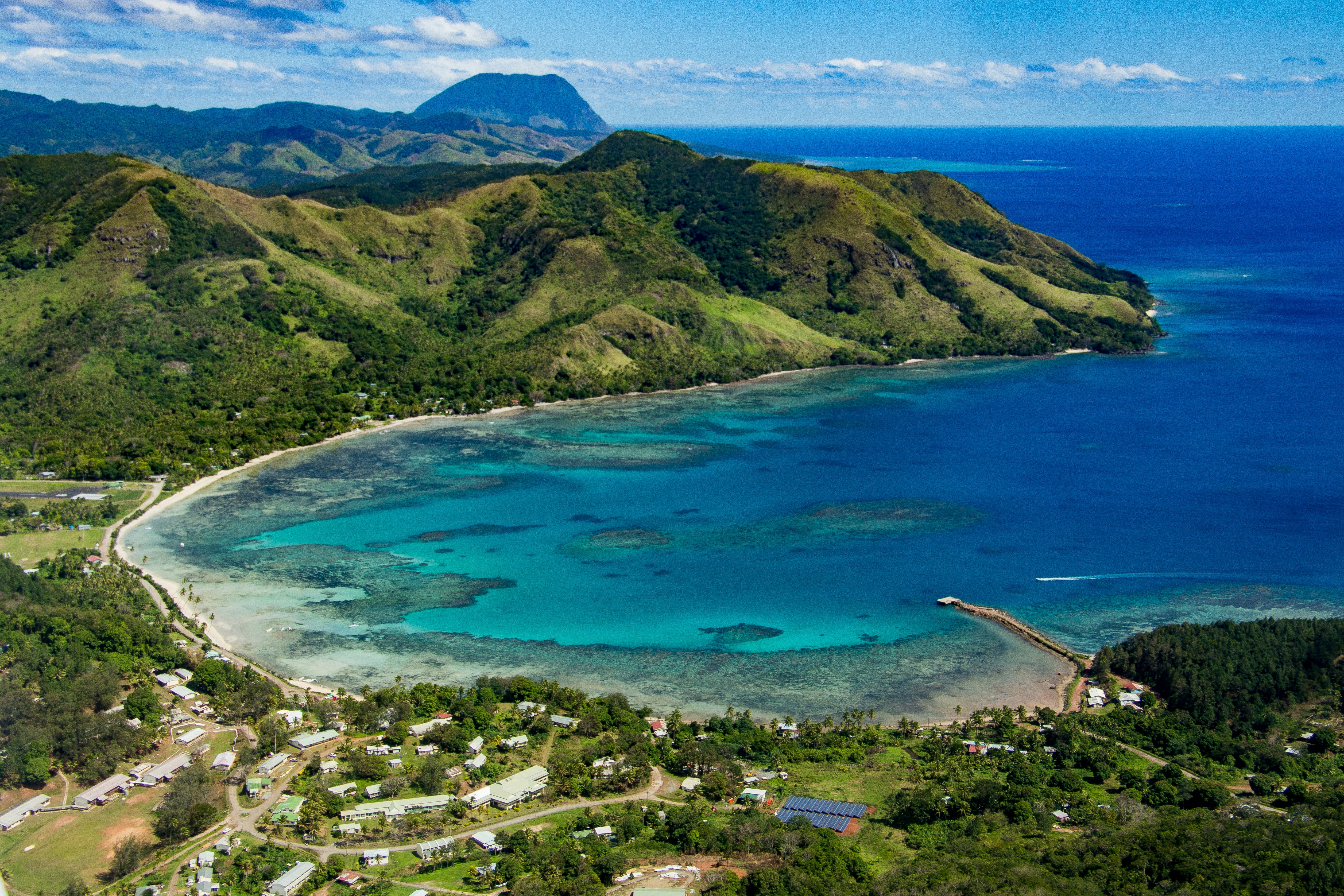 A small coastal village in a curved bay at the foot of woodland-covered hills.