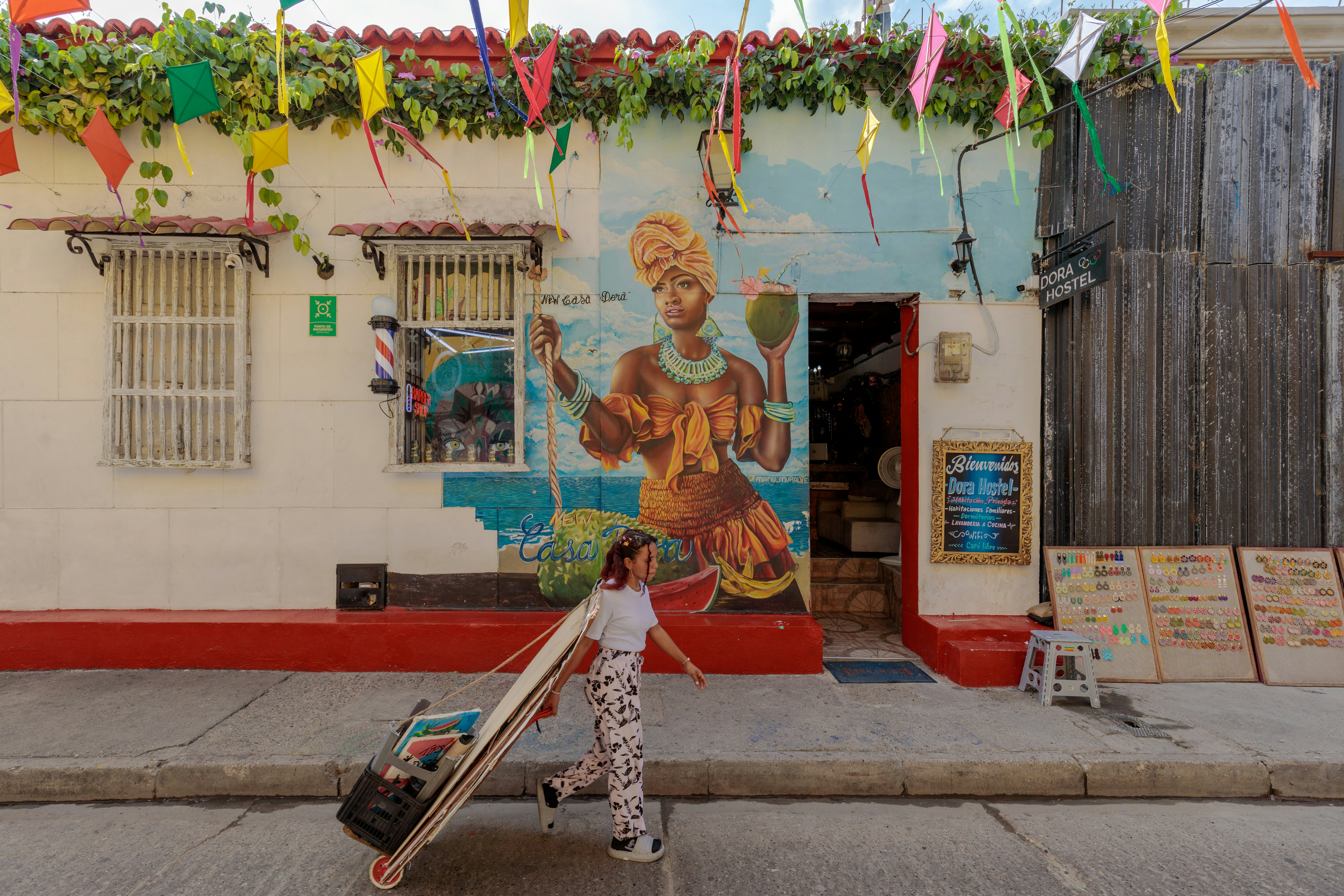 A woman holding artwork walks past a mural