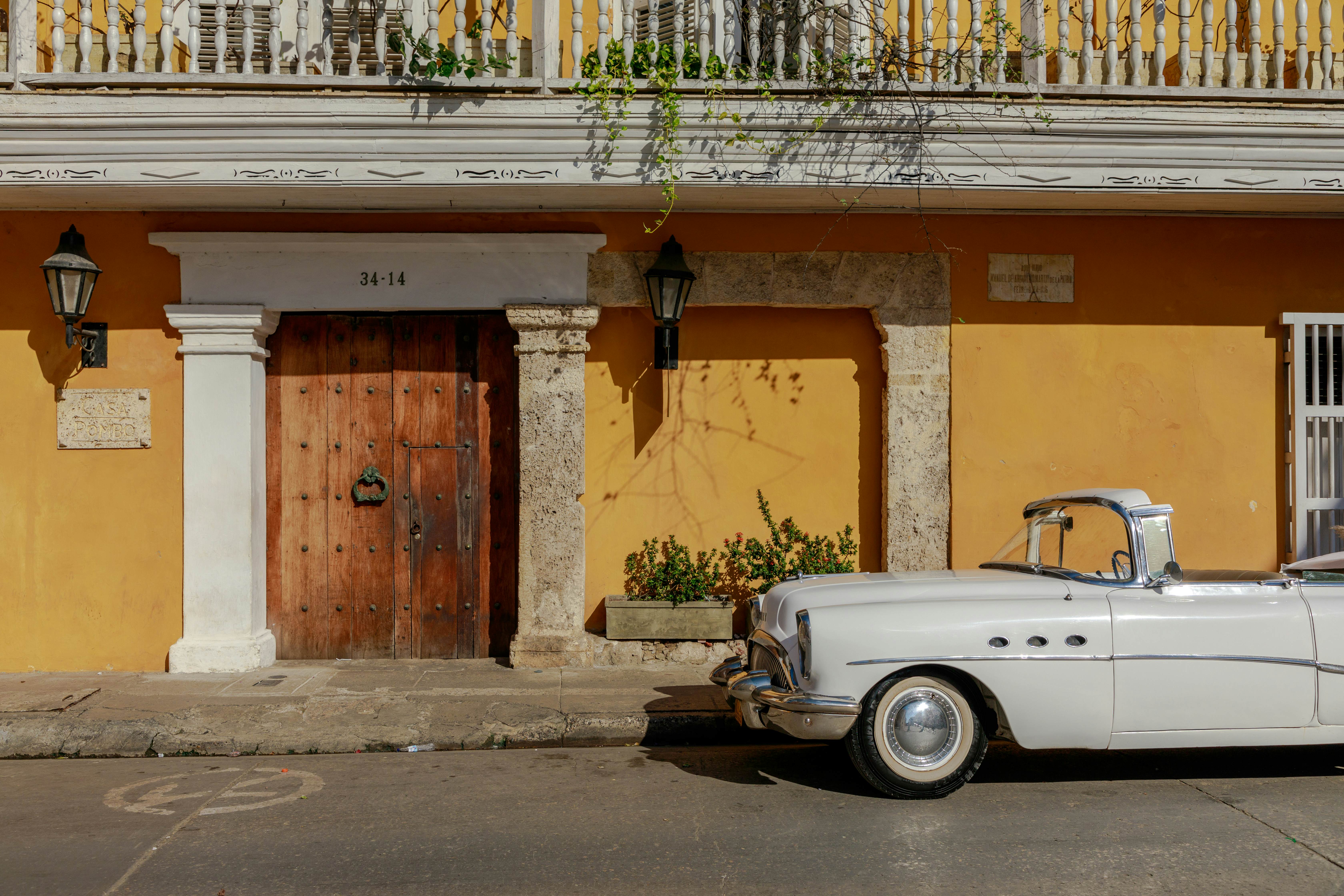 Cartagena - Col - 21/12/2024
Classic cars are one of the most iconic attractions in Cartagena, used for both sightseeing tours through the historic center and for the famous weddings that fill the streets with elegance. These vintage vehicles, with their nostalgic charm, provide an evocative and fun experience, transporting visitors back in time as they explore the city’s main landmarks. Whether cruising along the walls or visiting the most important plazas, classic cars become a central part of the Cartagena experience, especially when they are part of wedding ceremonies that add a touch of glamour to the city streets.
Tall Wooden Doors: Designed to accommodate carriages and horses, these doors are massive and made from solid wood. Their bronze knockers, often intricately designed, reflect the social status of the families who once resided there.