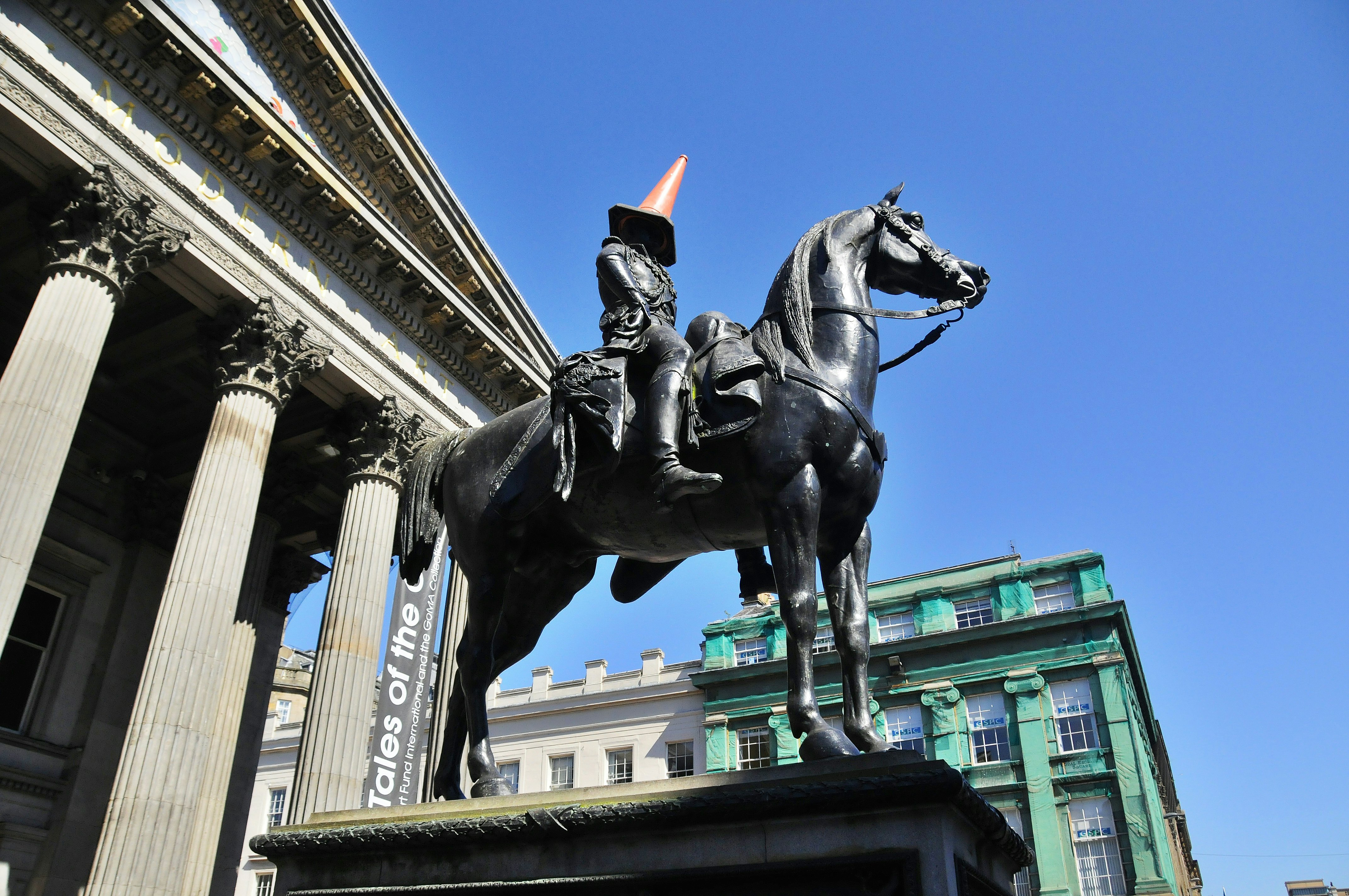 A traffic cone on top of the Duke of Wellington statue in front of Glasgow's Gallery of Modern Art, Scotland.