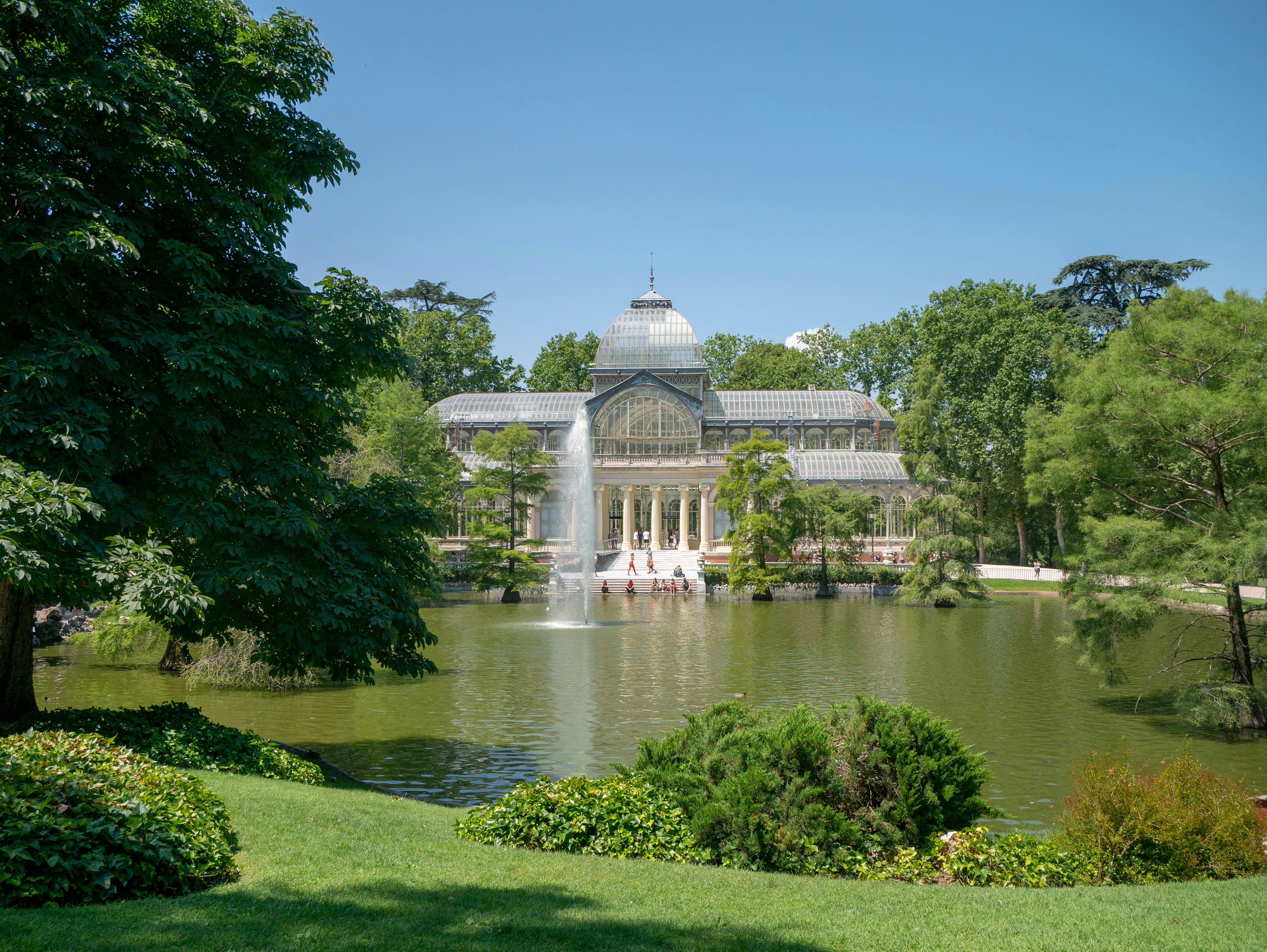 Glass building seen across pond with fountain.