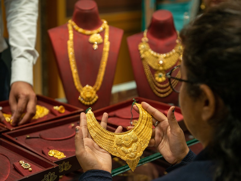 Woman holding a gold necklace.