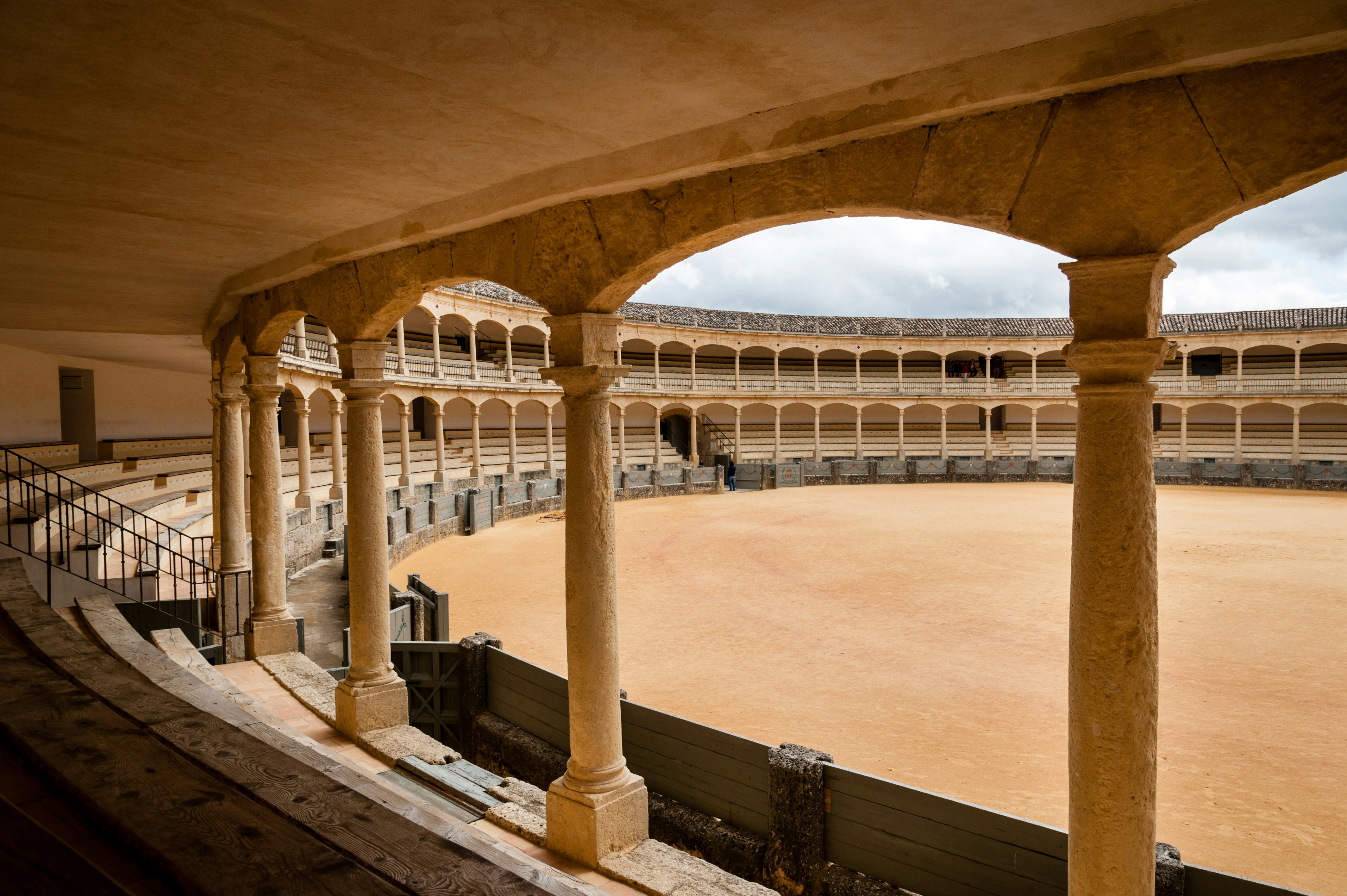 The interior of a bullring with two tiers of seating each with five raised rows and 136 pillars.