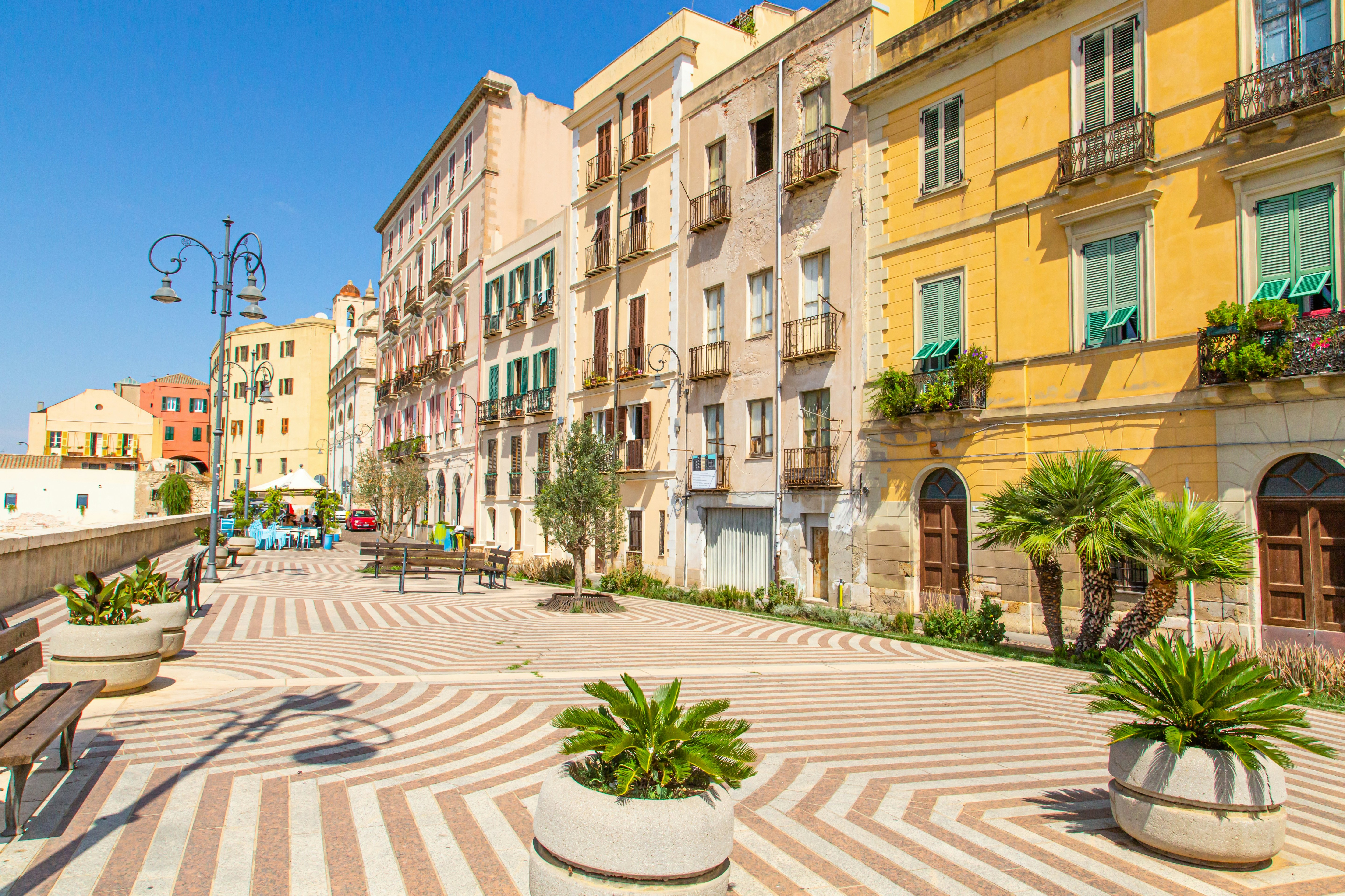 Colorful houses line a street with a striped sidewalk in the historic center of a city.