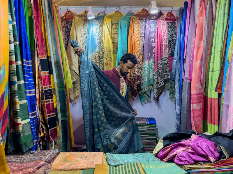 A sari vendor folds saris in his stall.