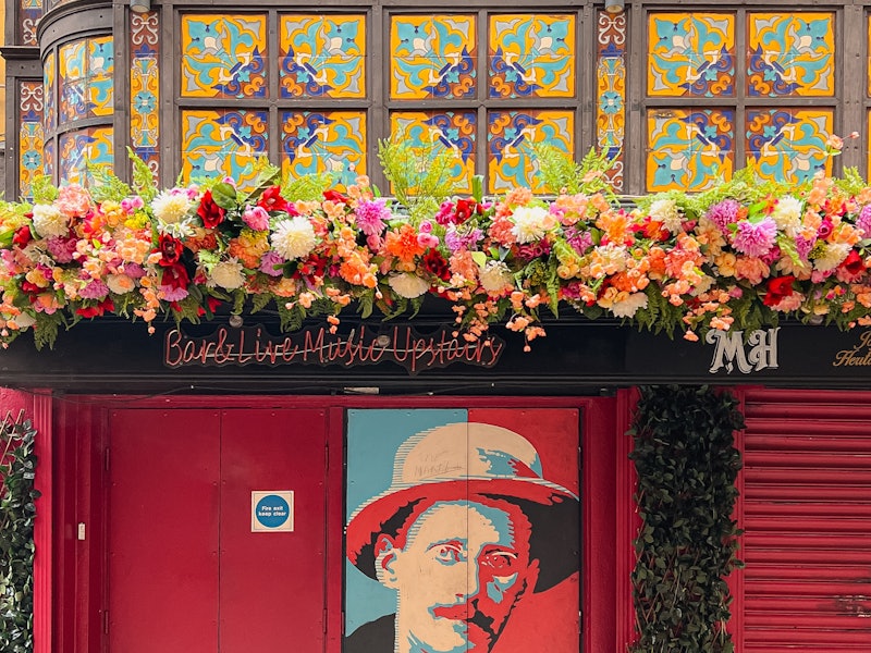 Street art with floral decor around a street art poster with the word JOYCE on it and a red wall in the historic center and stained glass