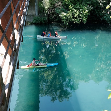 People kayaking under a bridge