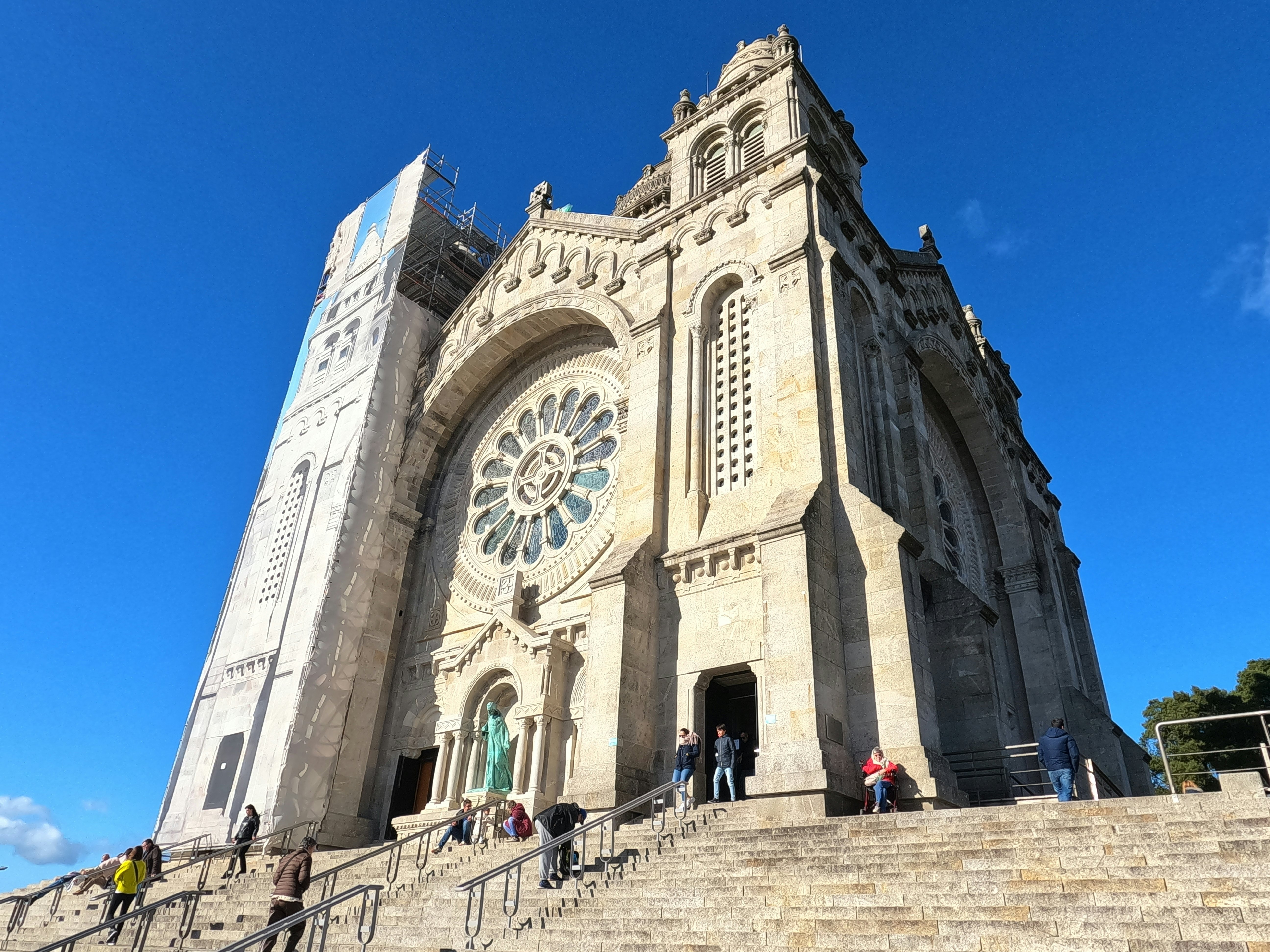 Stairs lead up to a large church that stands tall against a blue sky.