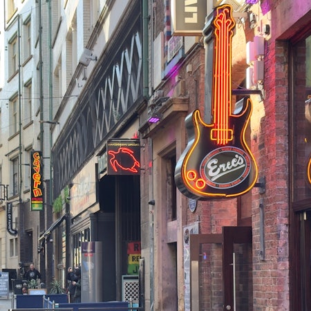 Neon signs outside bars on a pedestrianized street