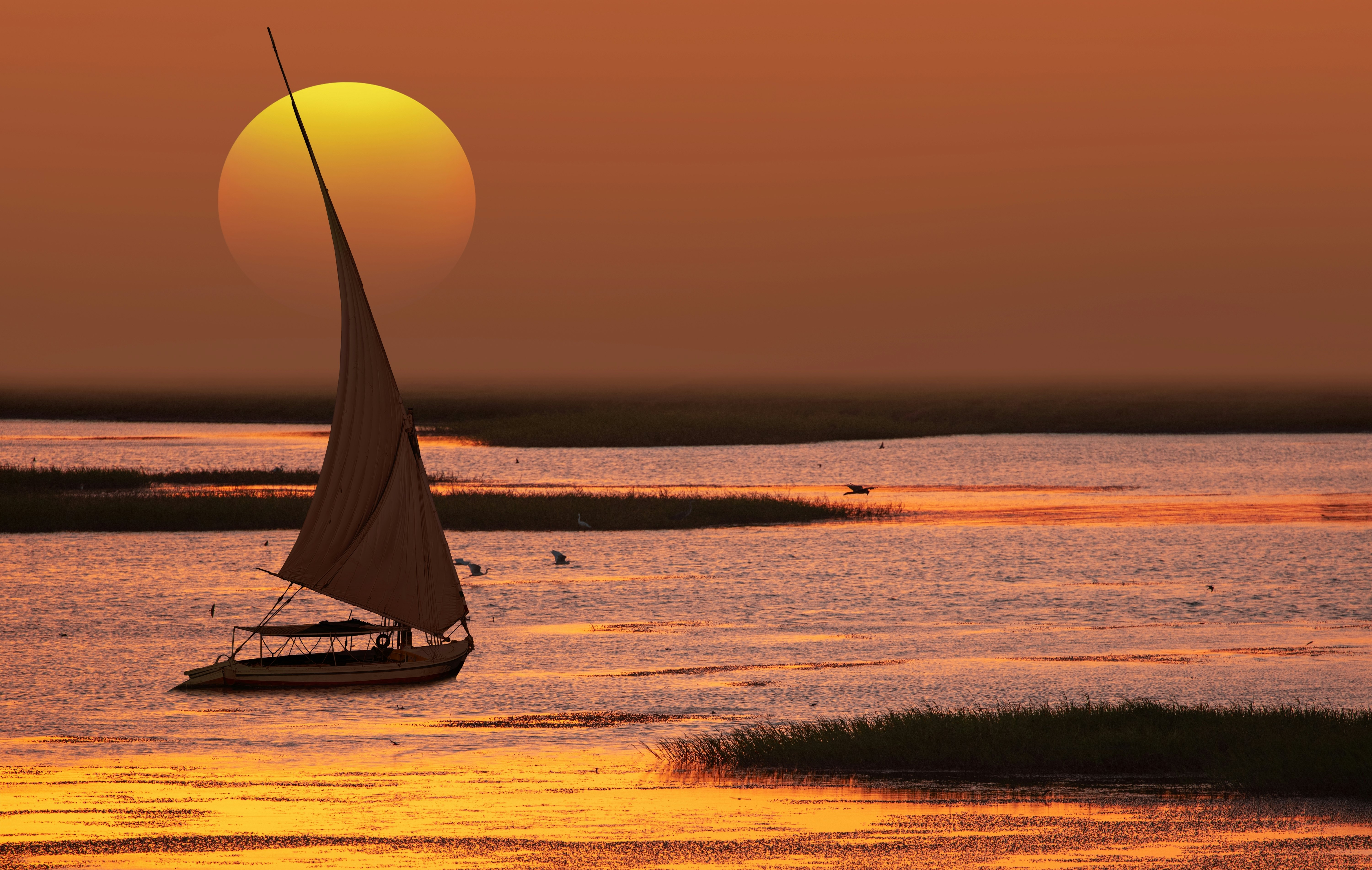 A small sailboat on waters at sunset