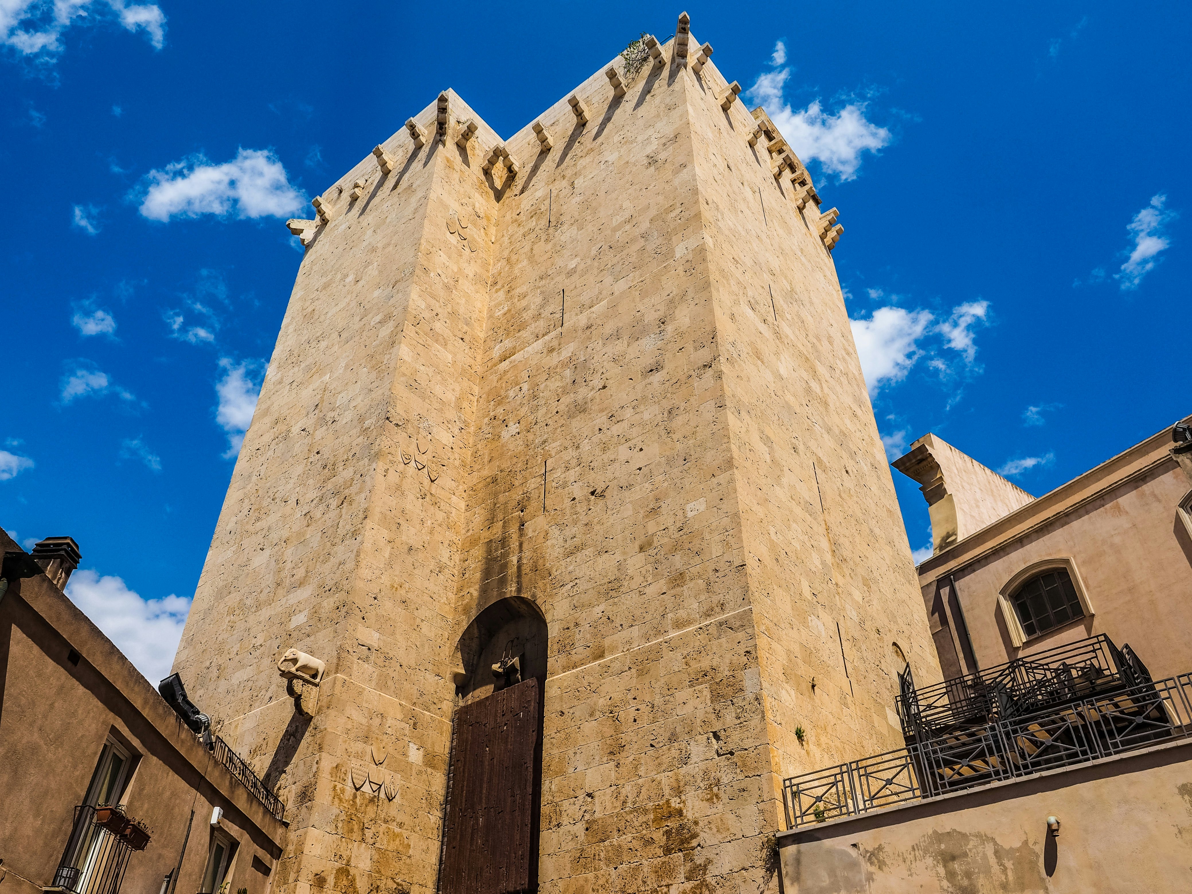 An imposing medieval stone tower with no windows stands below a blue sky.