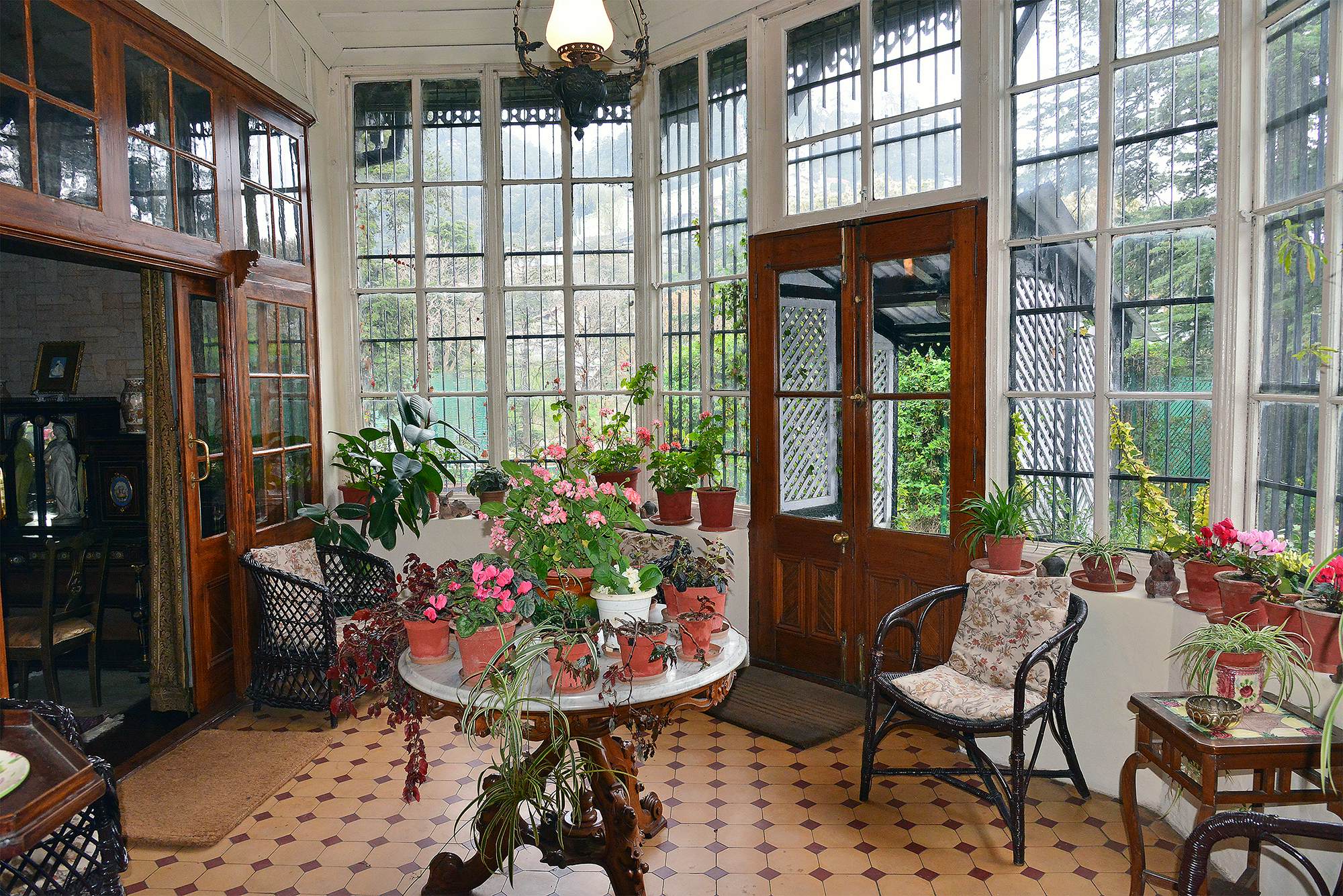 A conservatory with flower-filled pots on a central table.