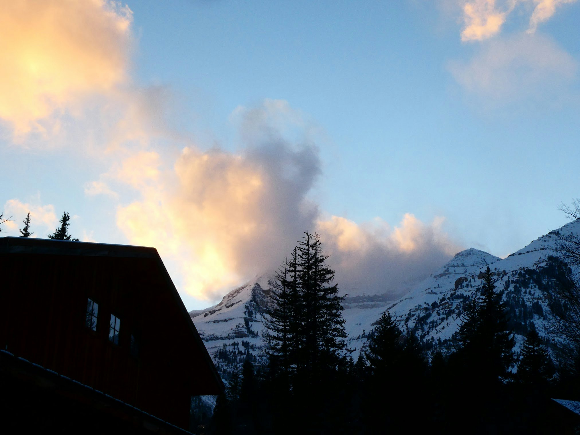 A cloudy sunset over snowy mountains