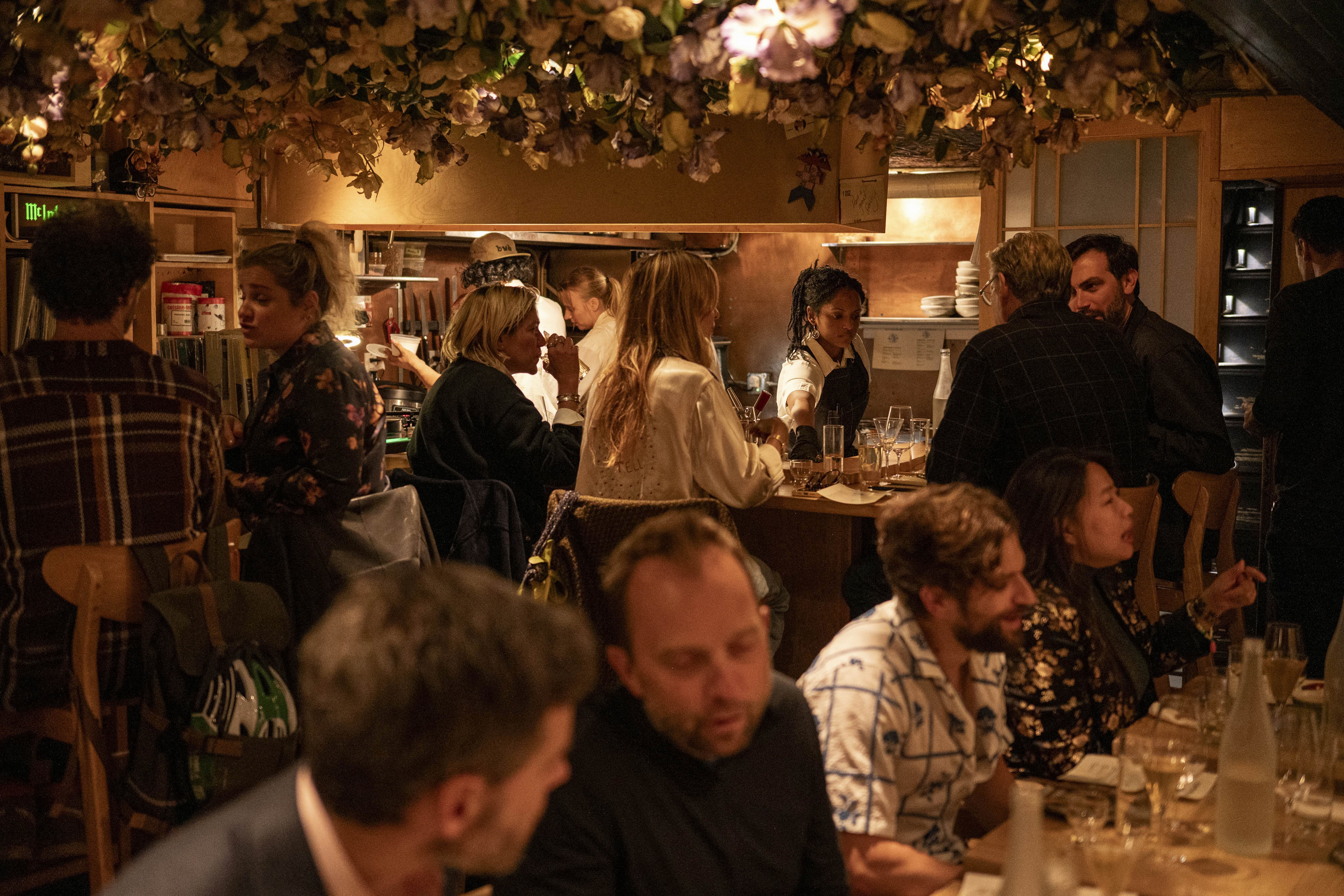 Diners seated at a bar and at tables in low light.