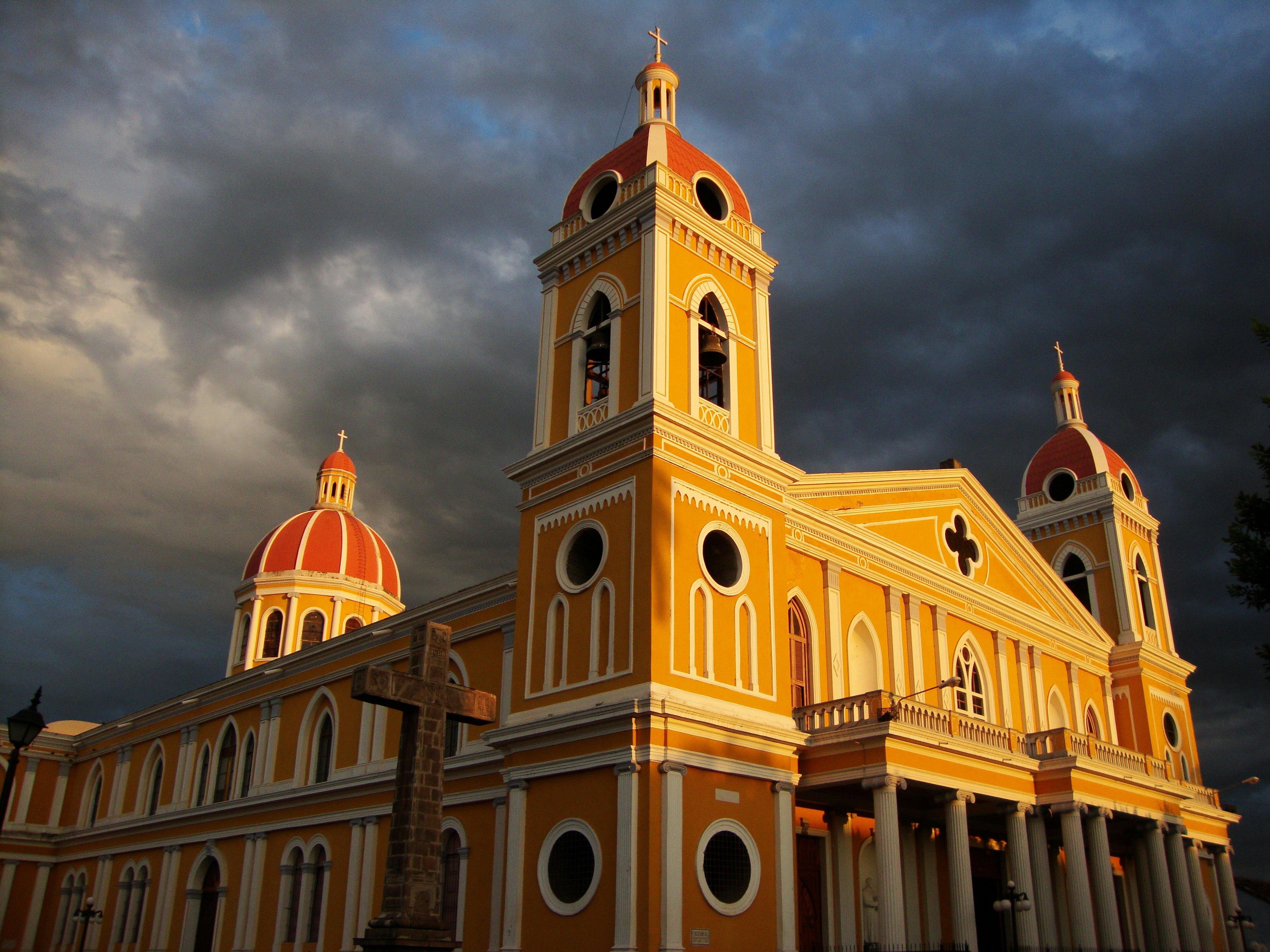 Coulds over a red-domed yellow cathedral bathed in sunlight.