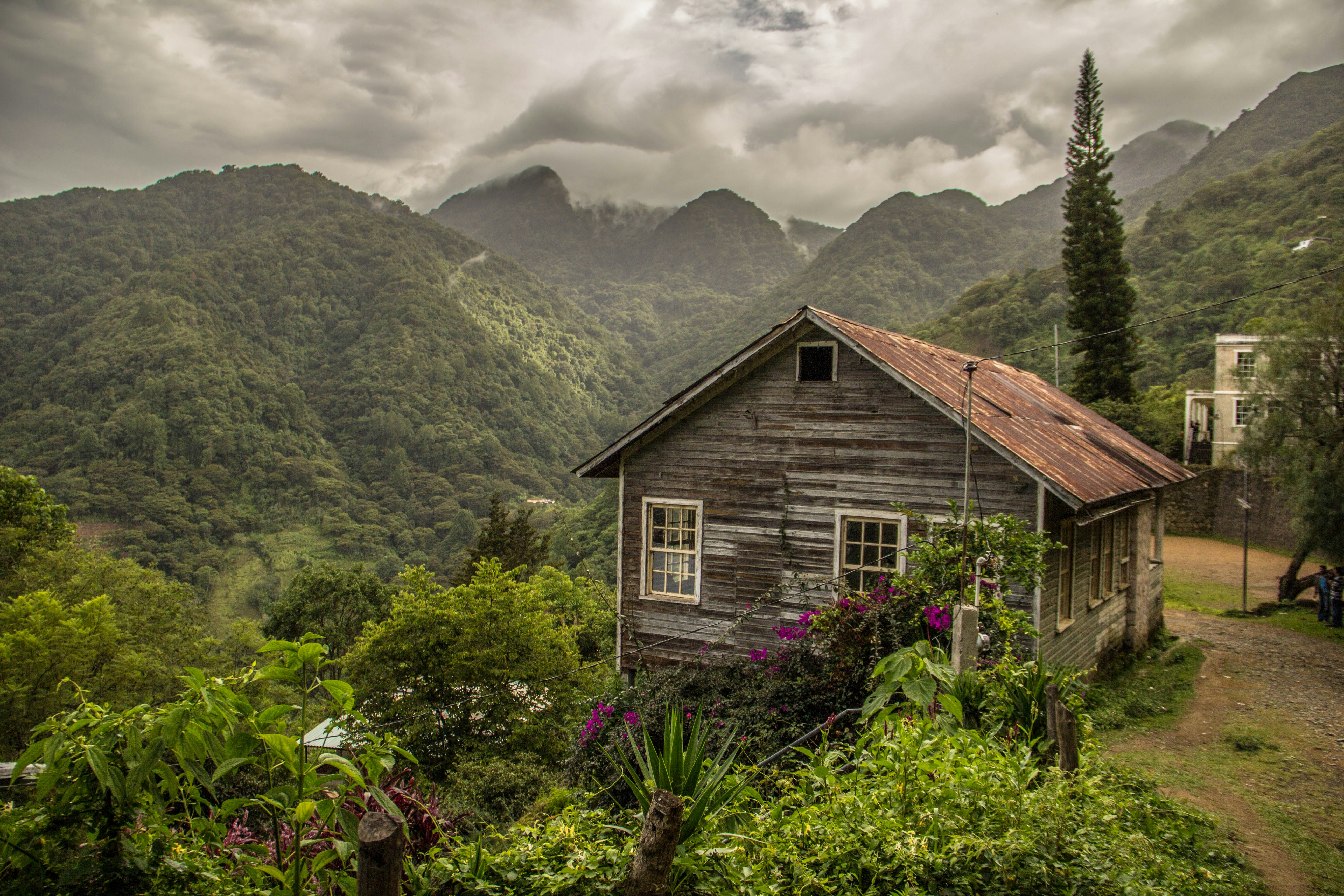 A wooden building at the edge of a mountain valley covered in forest.