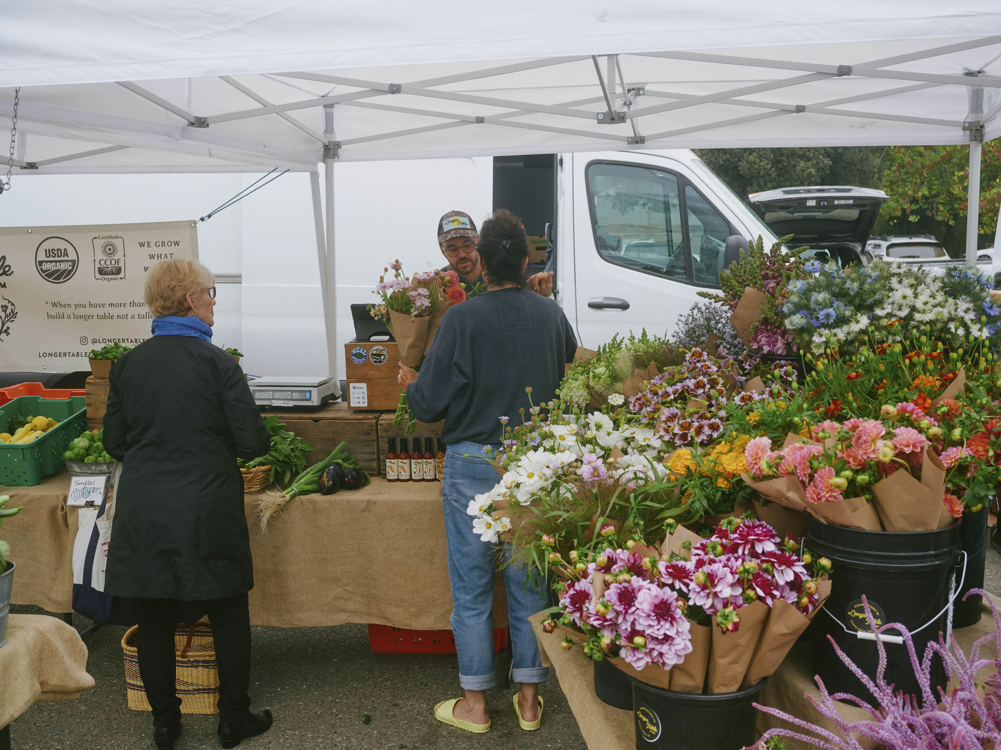 Two people purchase flowers from a stand. 