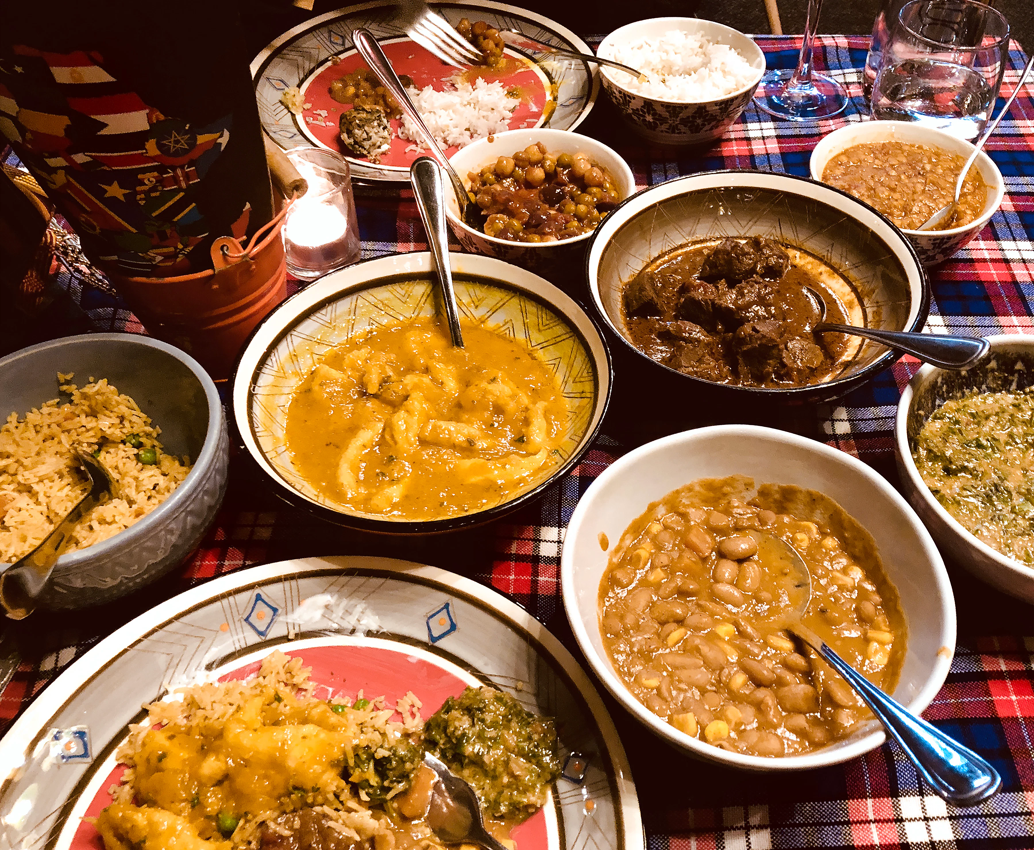 A table with bowls of various foods such as meats, beans and rice