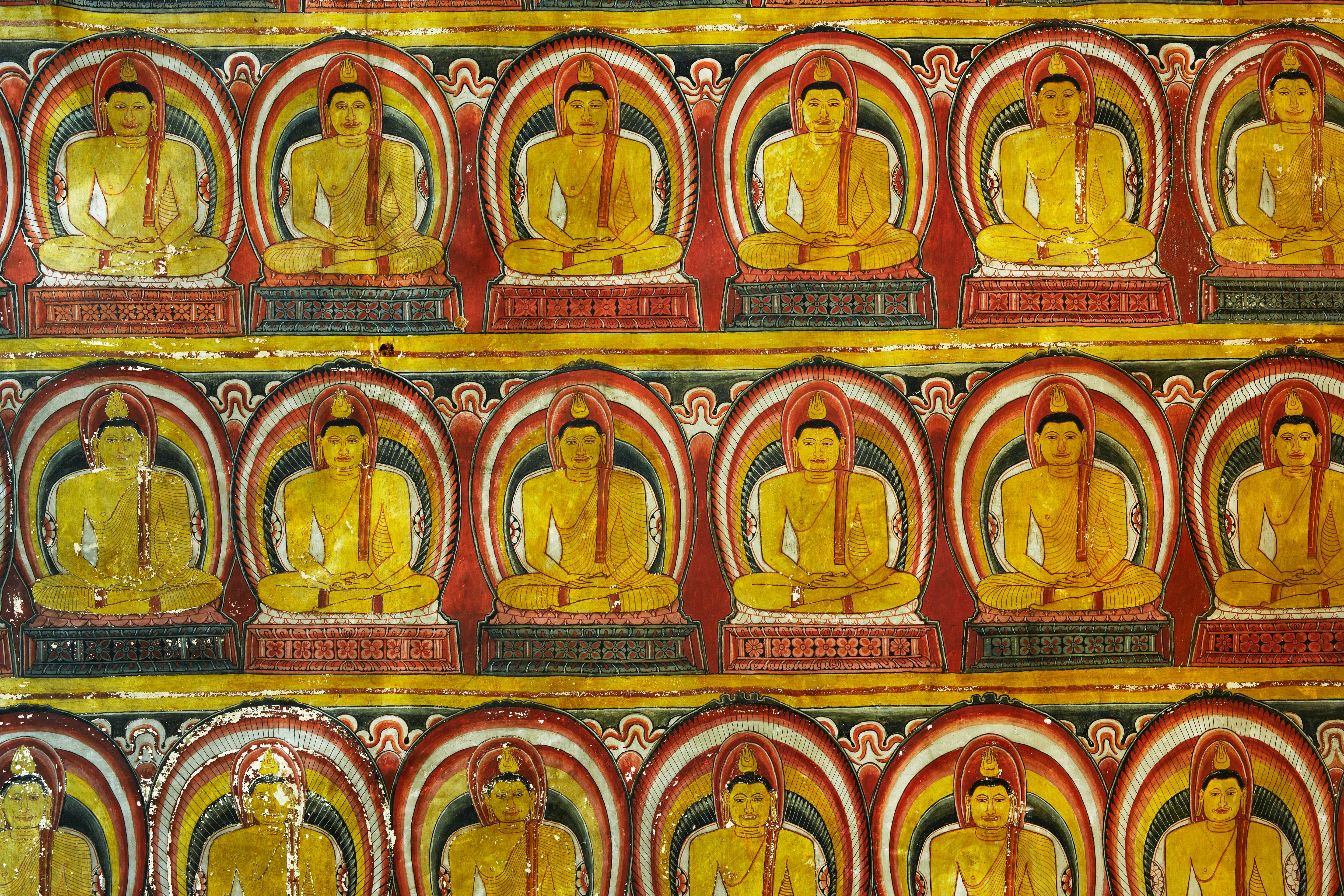  A fresco in red, gold and green pictures rows of Buddha at a cave in Sri Lanka.