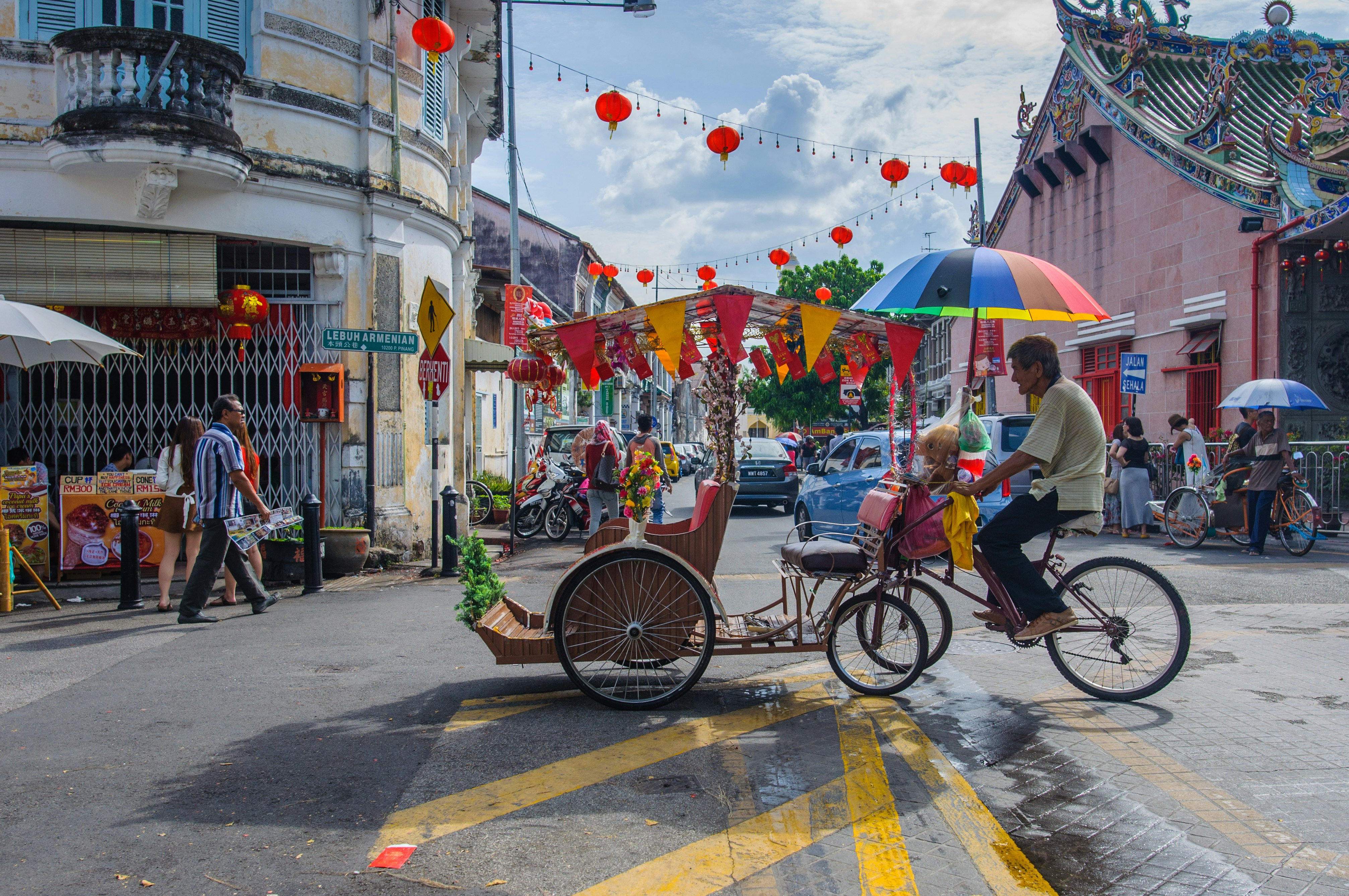 Man on a cycle with a rainbow umbrella over his head
