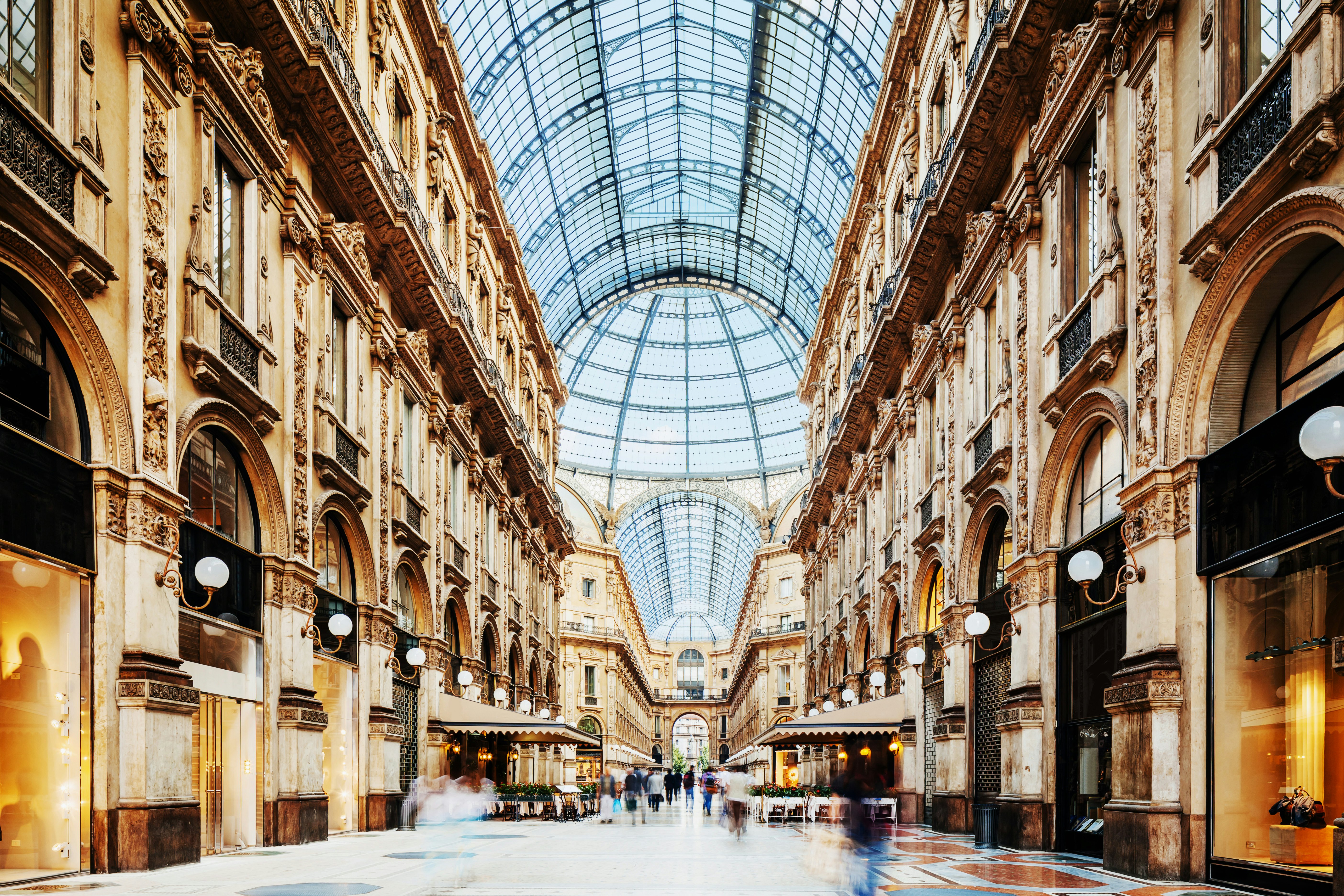 A vast upmarket shopping arcade with a large curved glass roof.