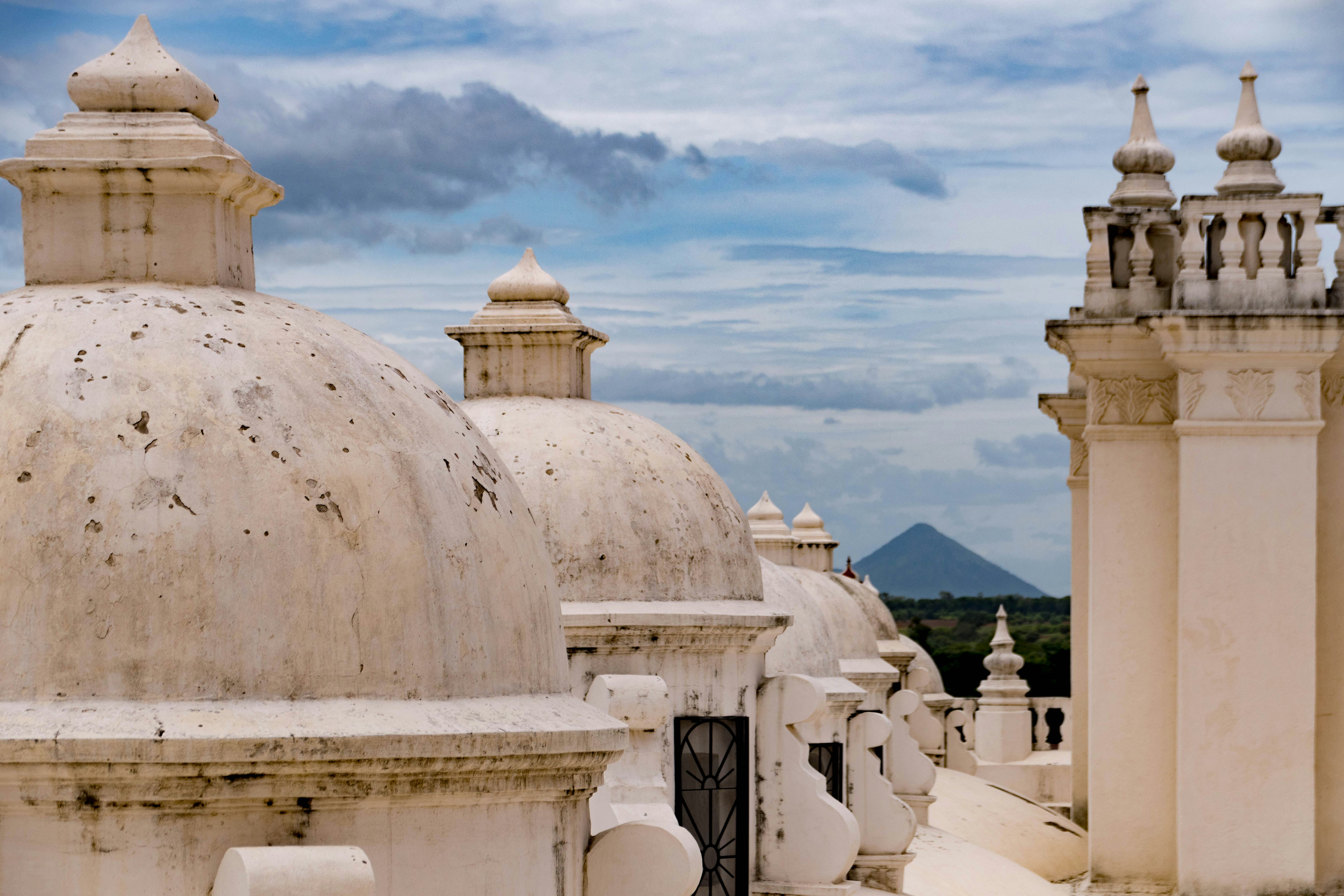 The top spires of a white church with a volcano in the background
