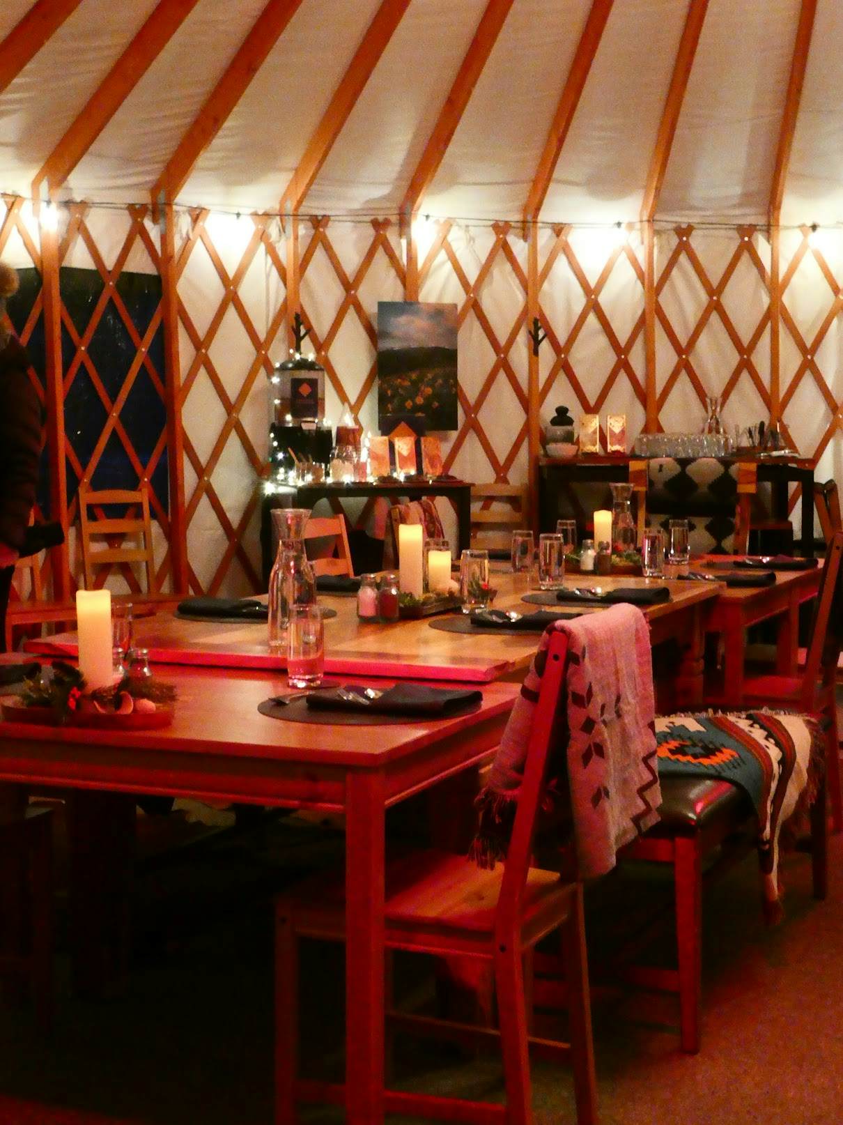 The inside of the yurt with candles and blankets. 